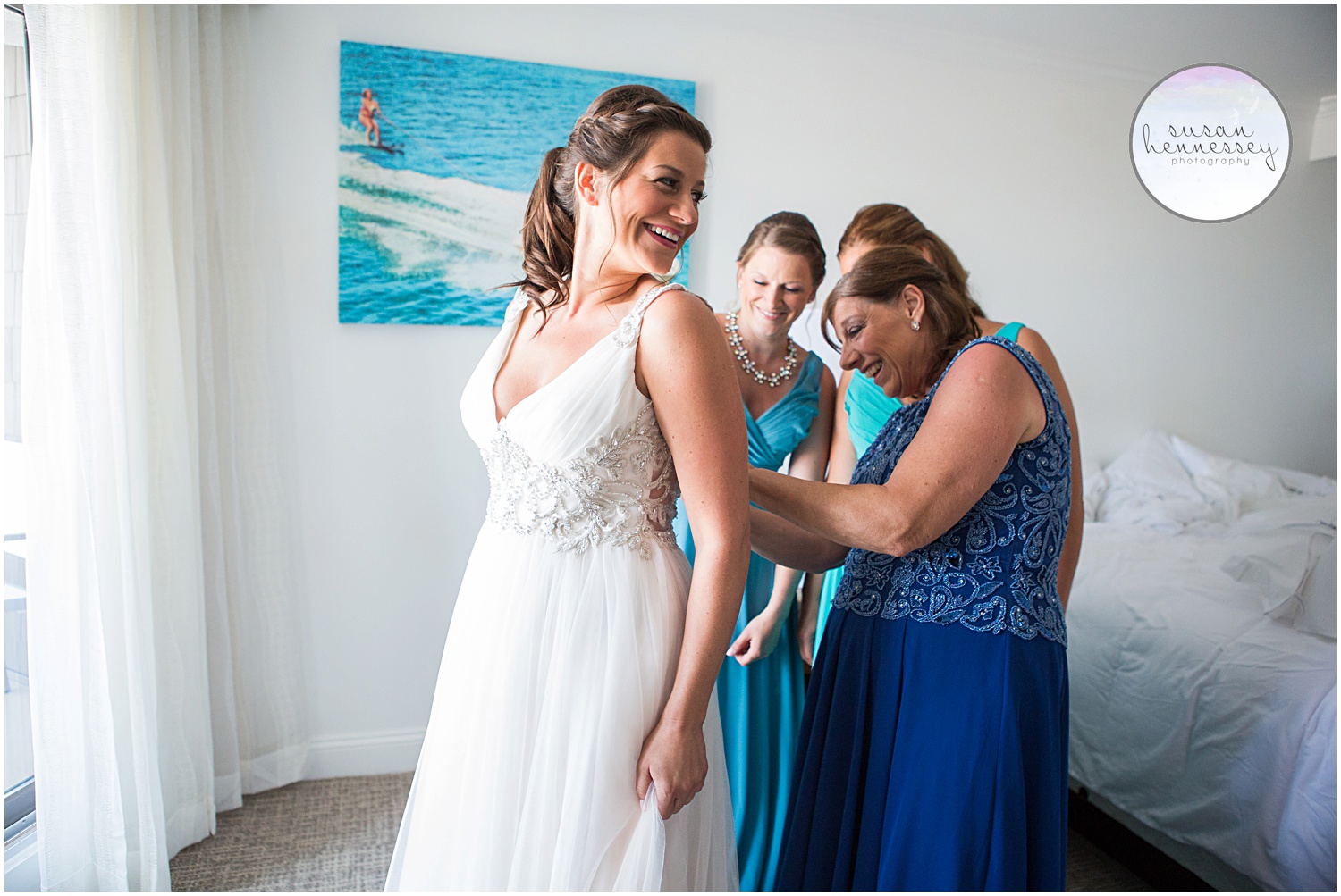 Bride's mother and sisters zip her into her gorgeous beachy wedding gown. 