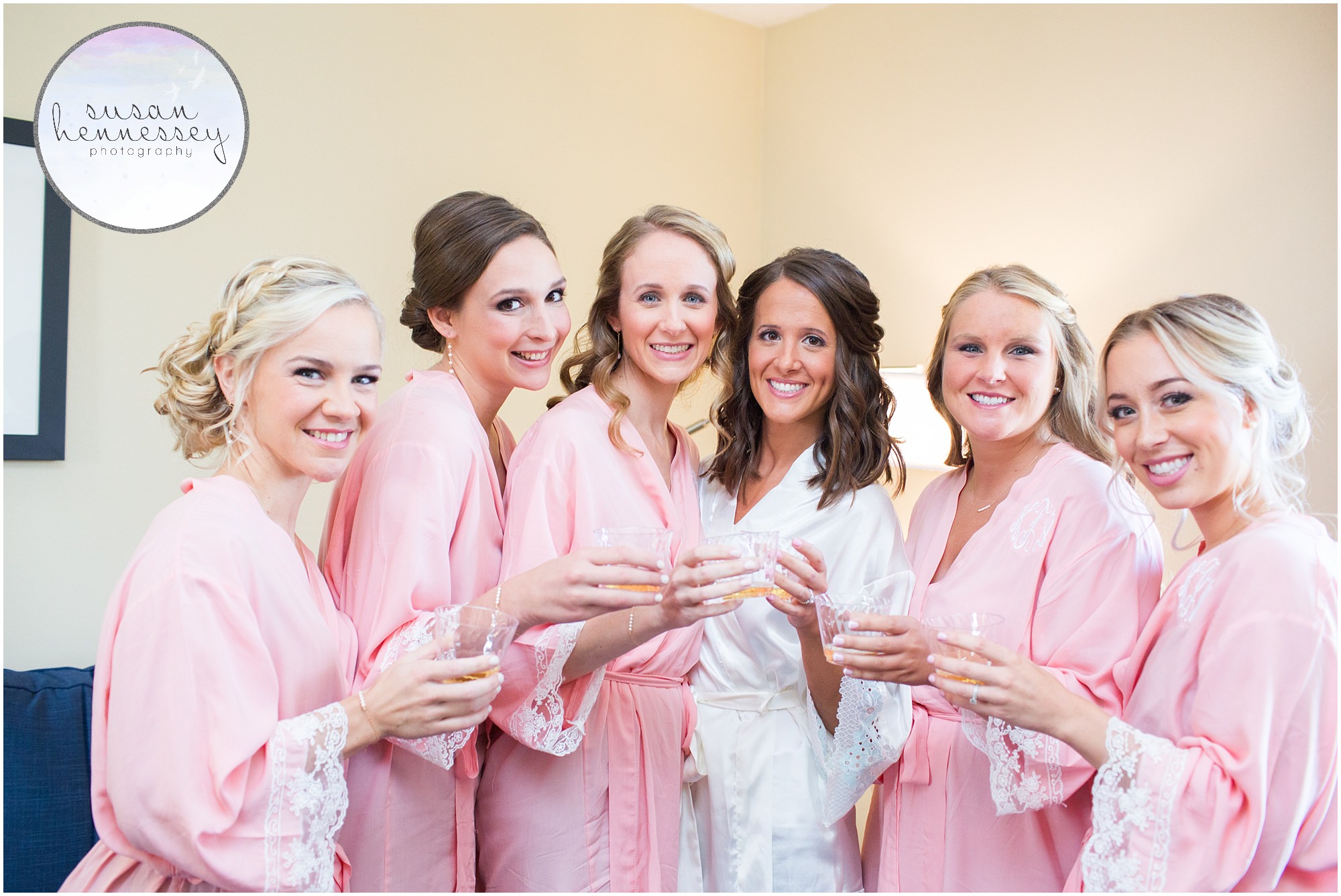 Bridesmaids in pink robes with glasses of champagne.