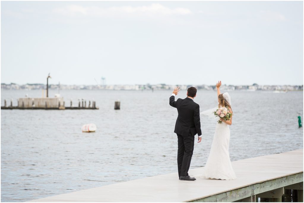 Couple on the dock wave at well wishers on a boat. 