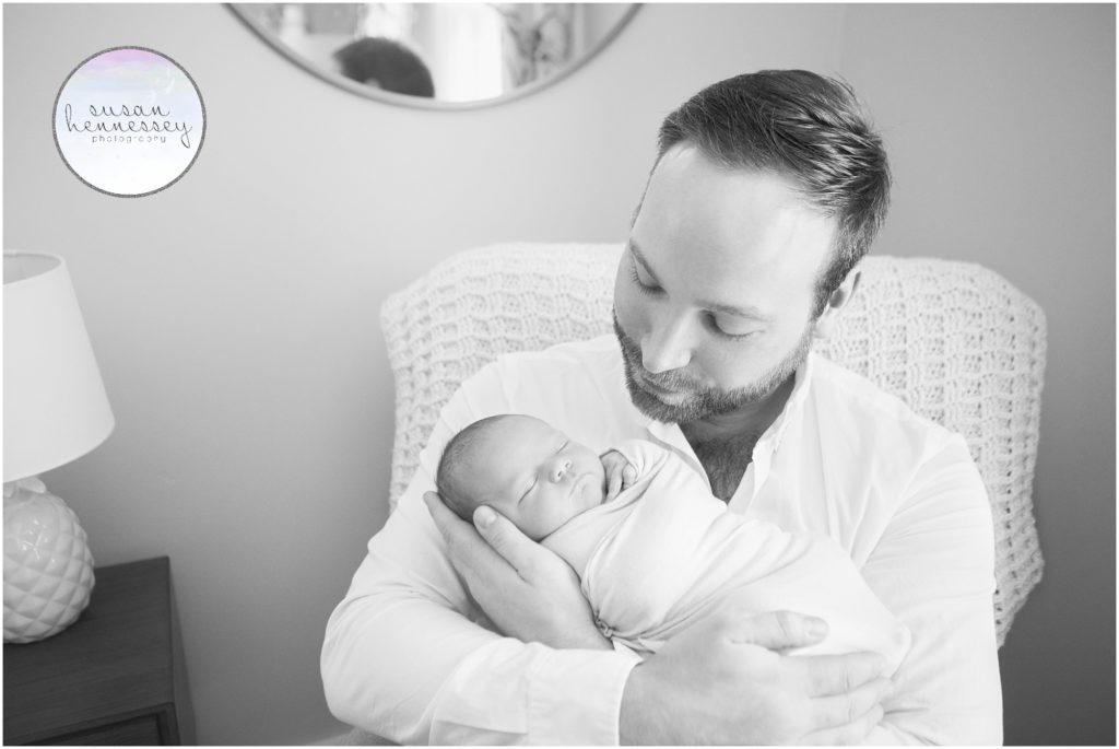 Black and white portrait of father and newborn in her nursery