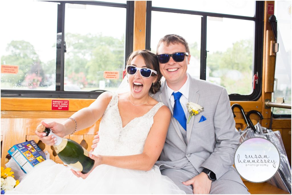 Happy bride and groom popping champagne on trolley after ceremony.