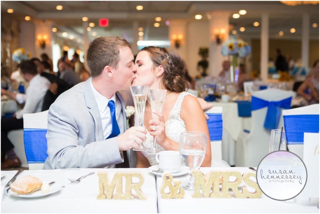 Bride and groom kiss at sweetheart table.