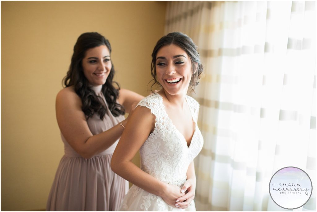 Maid of honor helps bride into her wedding gown.