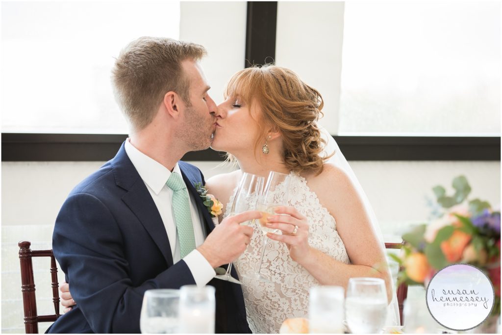 Bride and groom laugh kiss at sweetheart table at Windrift Hotel wedding