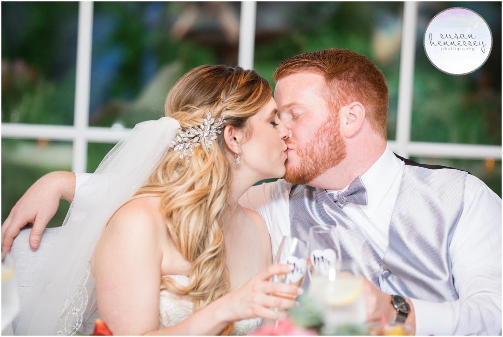 Bride and groom kiss at sweetheart table at Bradford Estate wedding reception