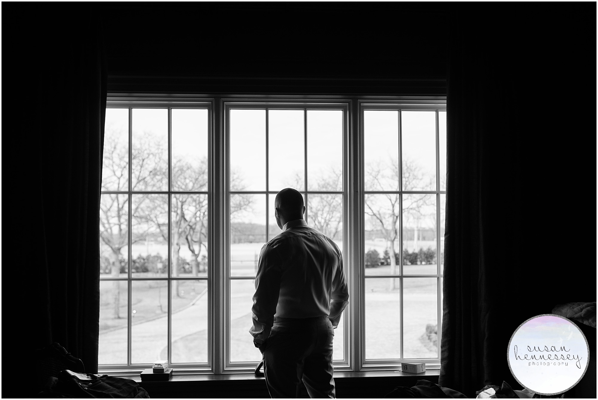 groom looking out window awaiting wedding 