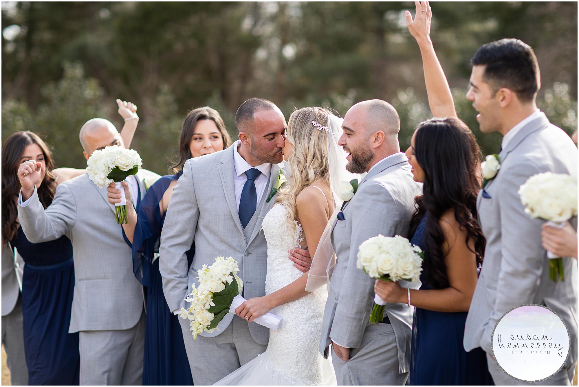 couple kisses in front of bridal party 