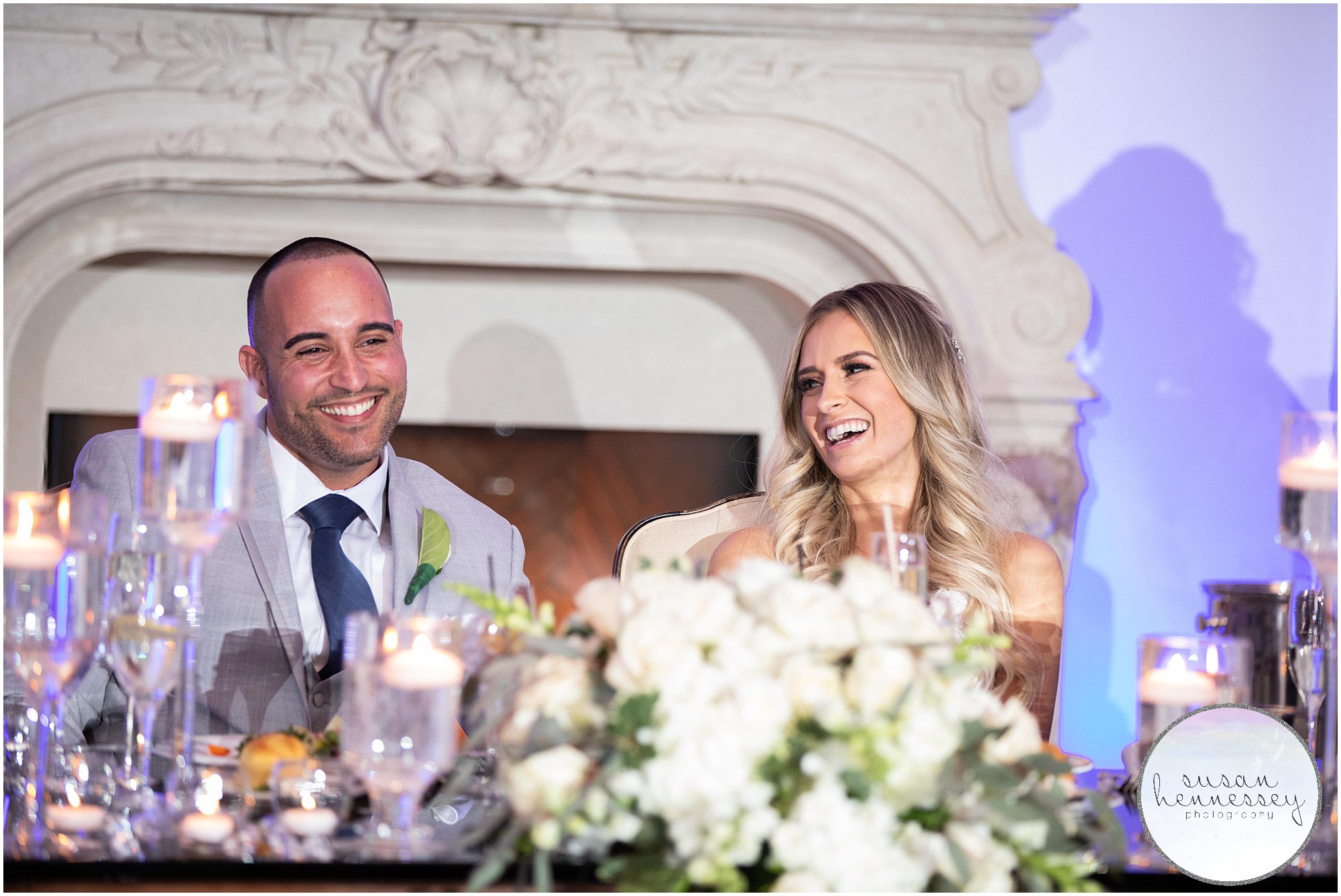 A bride and groom laugh during speeches.