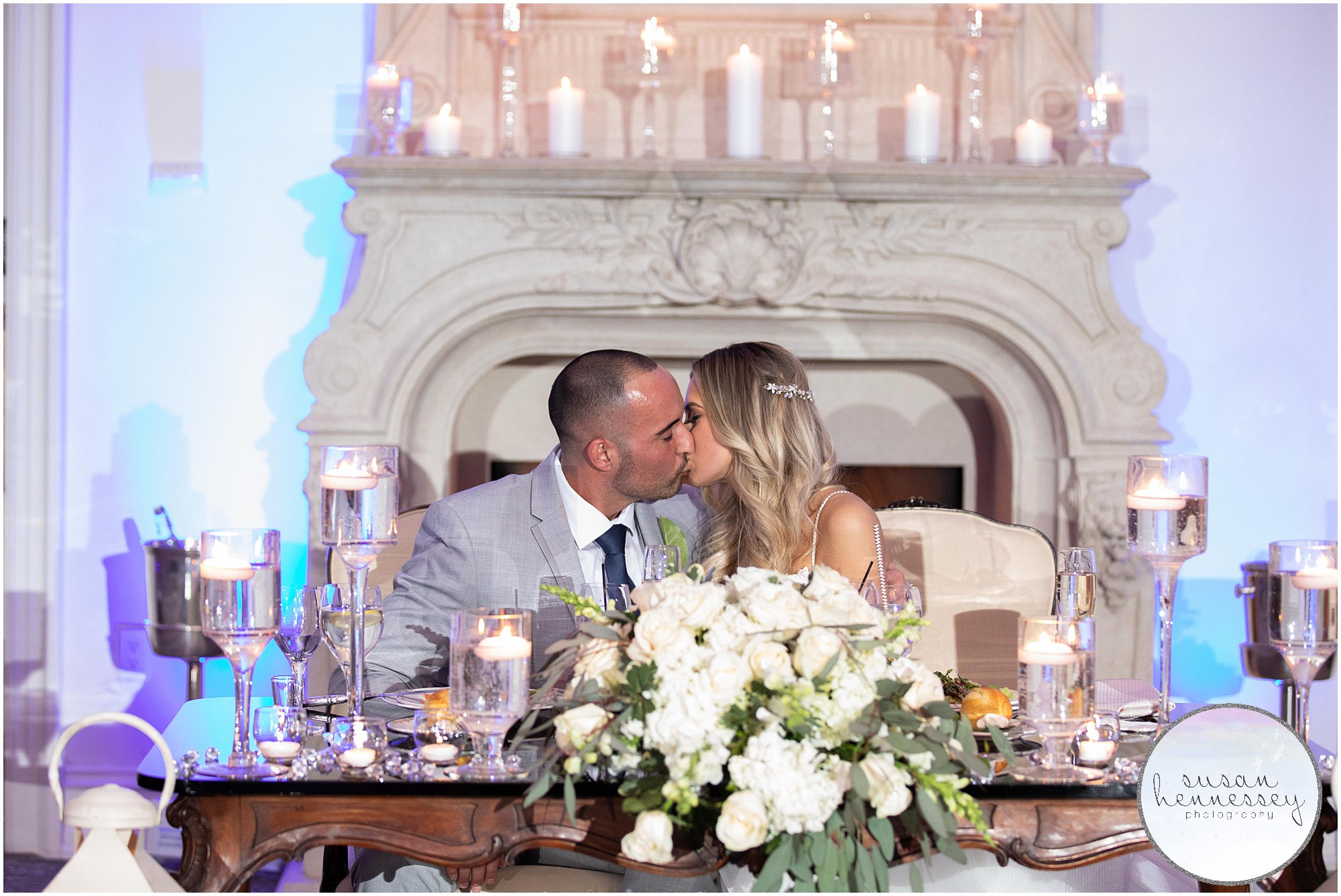 A bride and groom share a kiss at the sweetheart table of their winter wedding. 