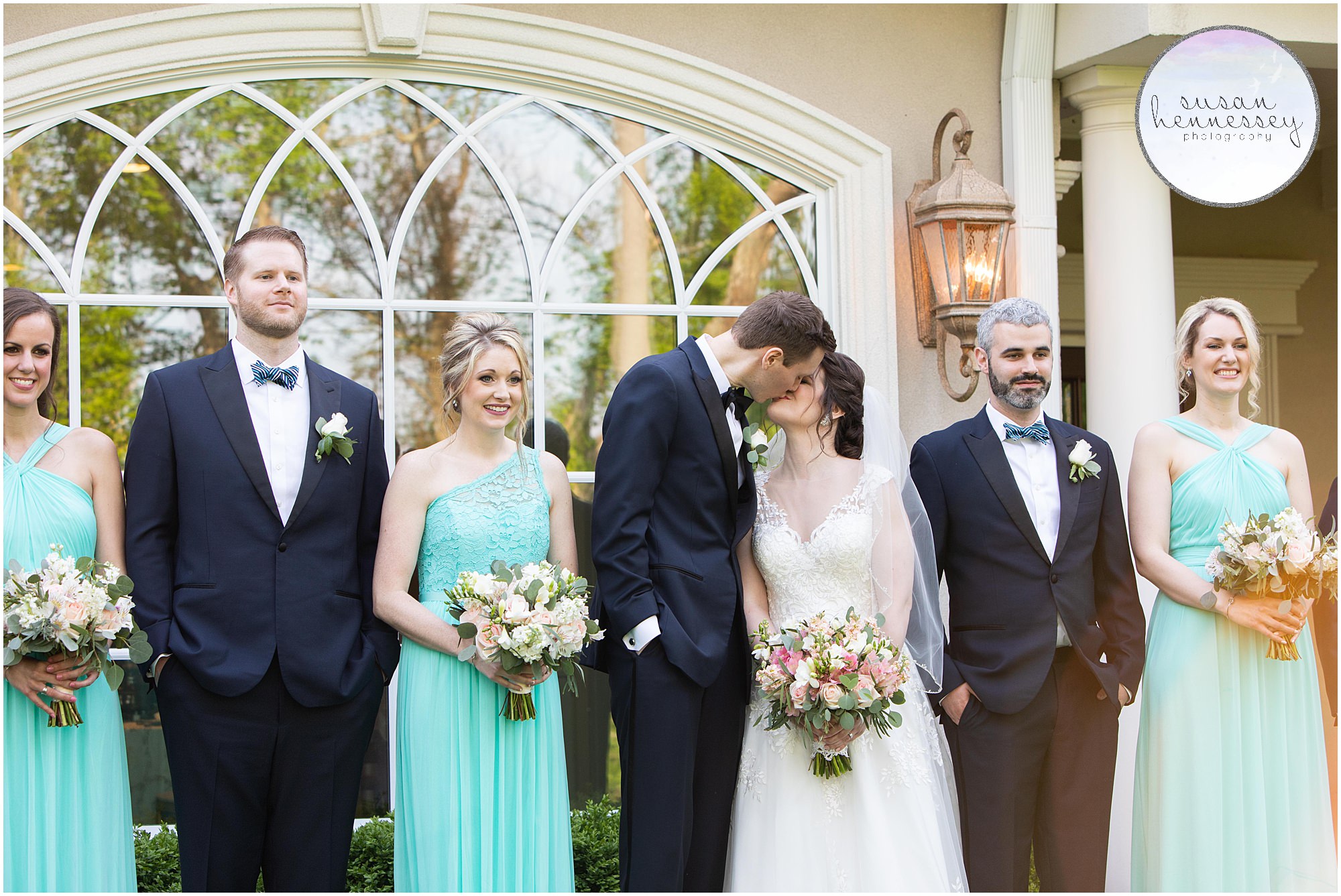 Bride and groom kiss during bridal party portraits