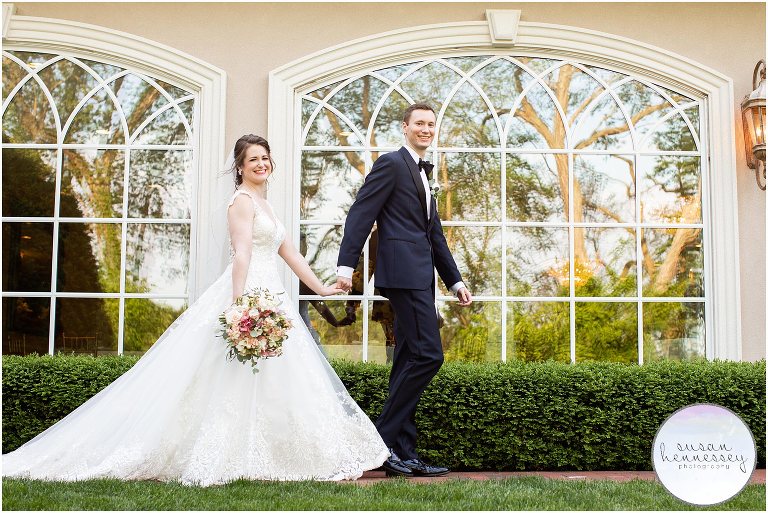 Bride and groom walk along unique windows at South Jersey wedding venue