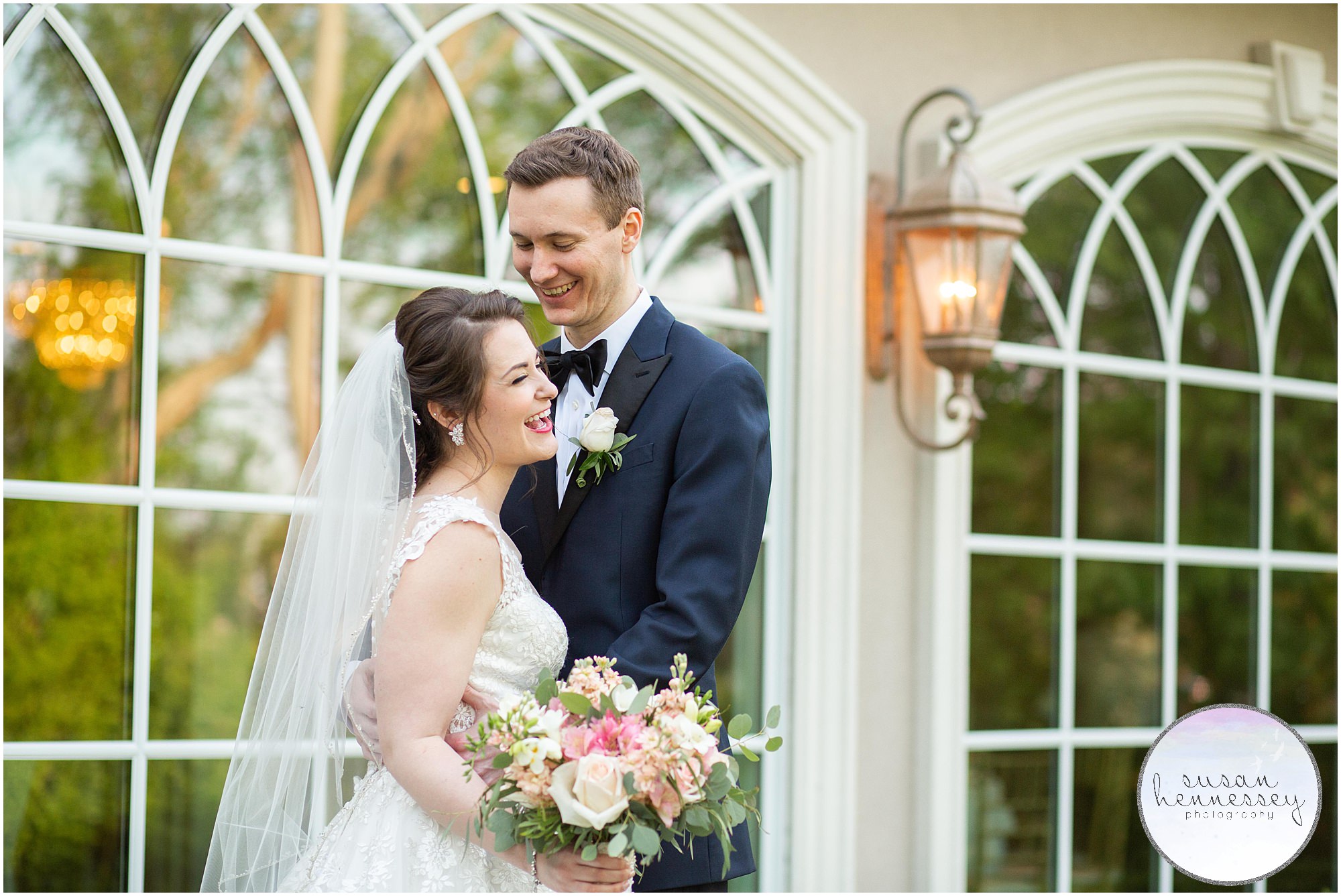 Bride and groom laugh in front of the windows at the Bradford Estate