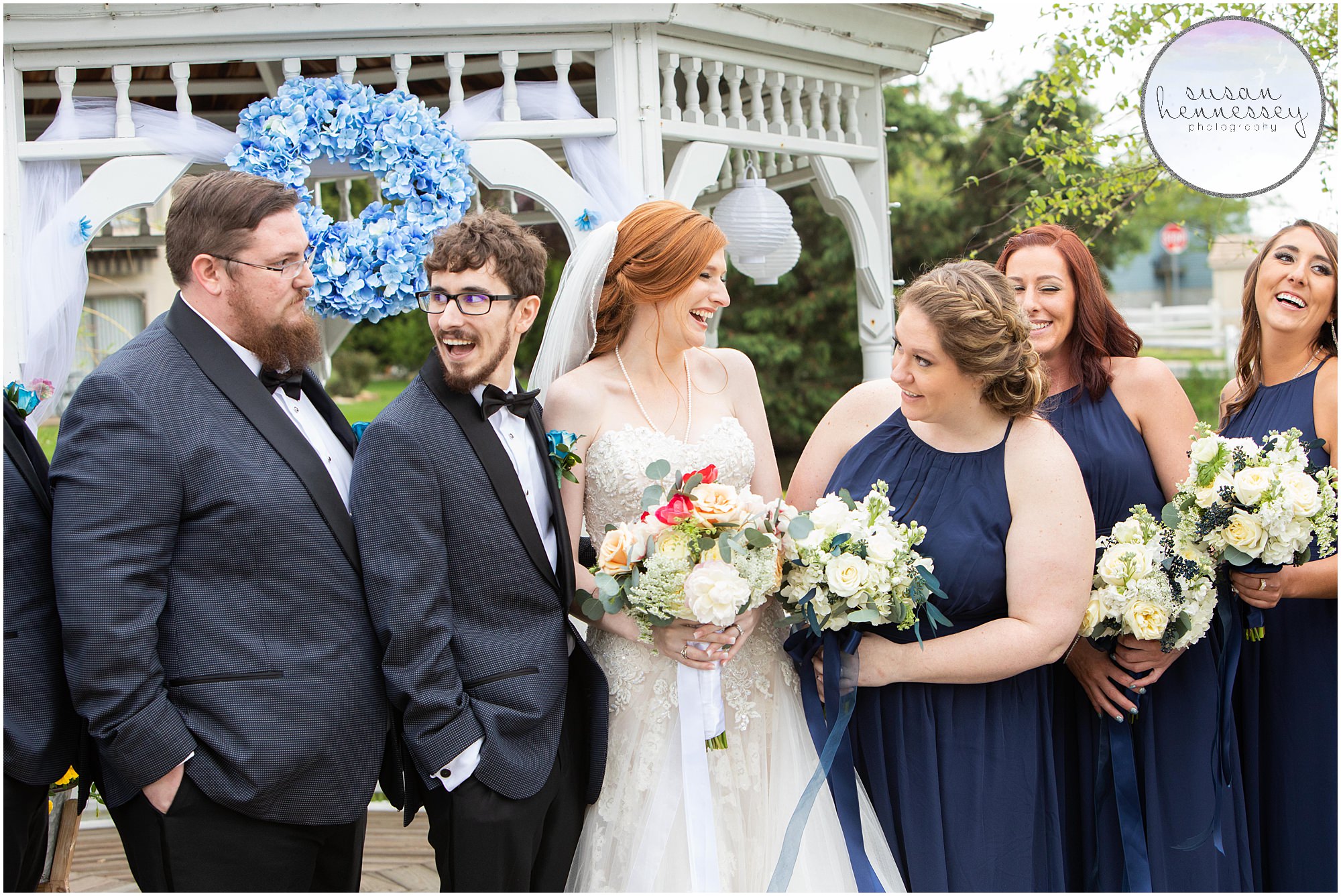 A bride and groom laugh with their bridal party.