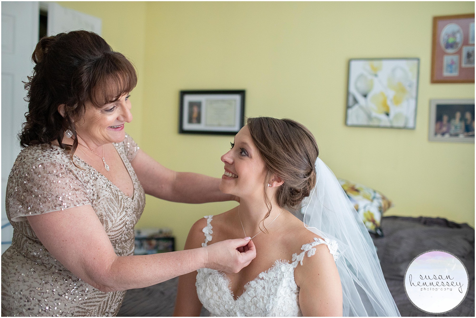 The bride's mother helps with her necklace.