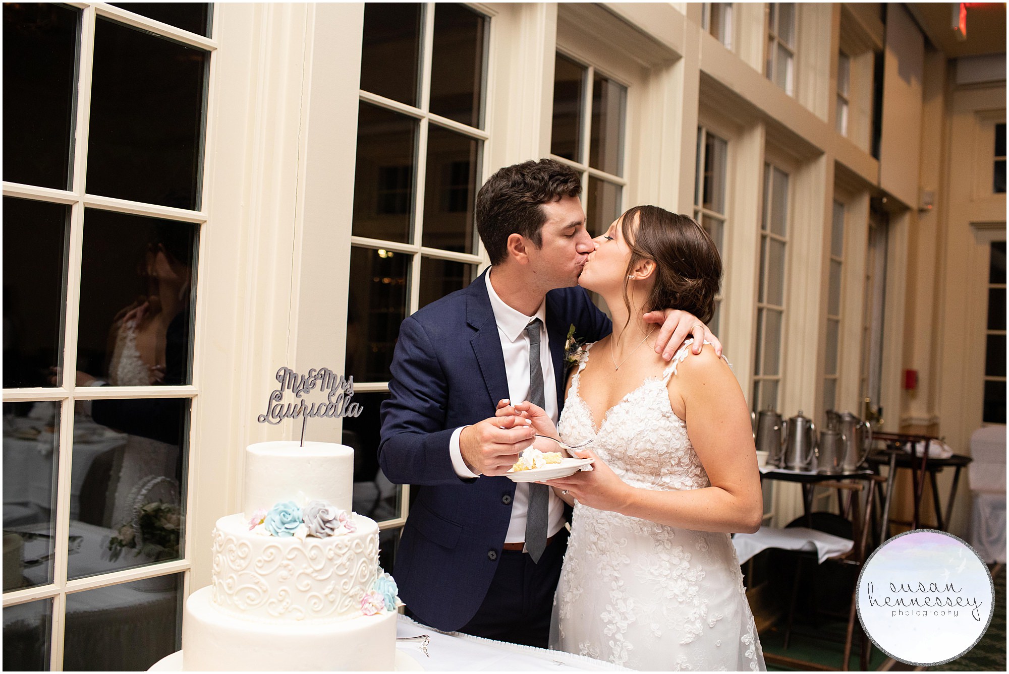 Bride and groom kiss after cutting cake on wedding day.