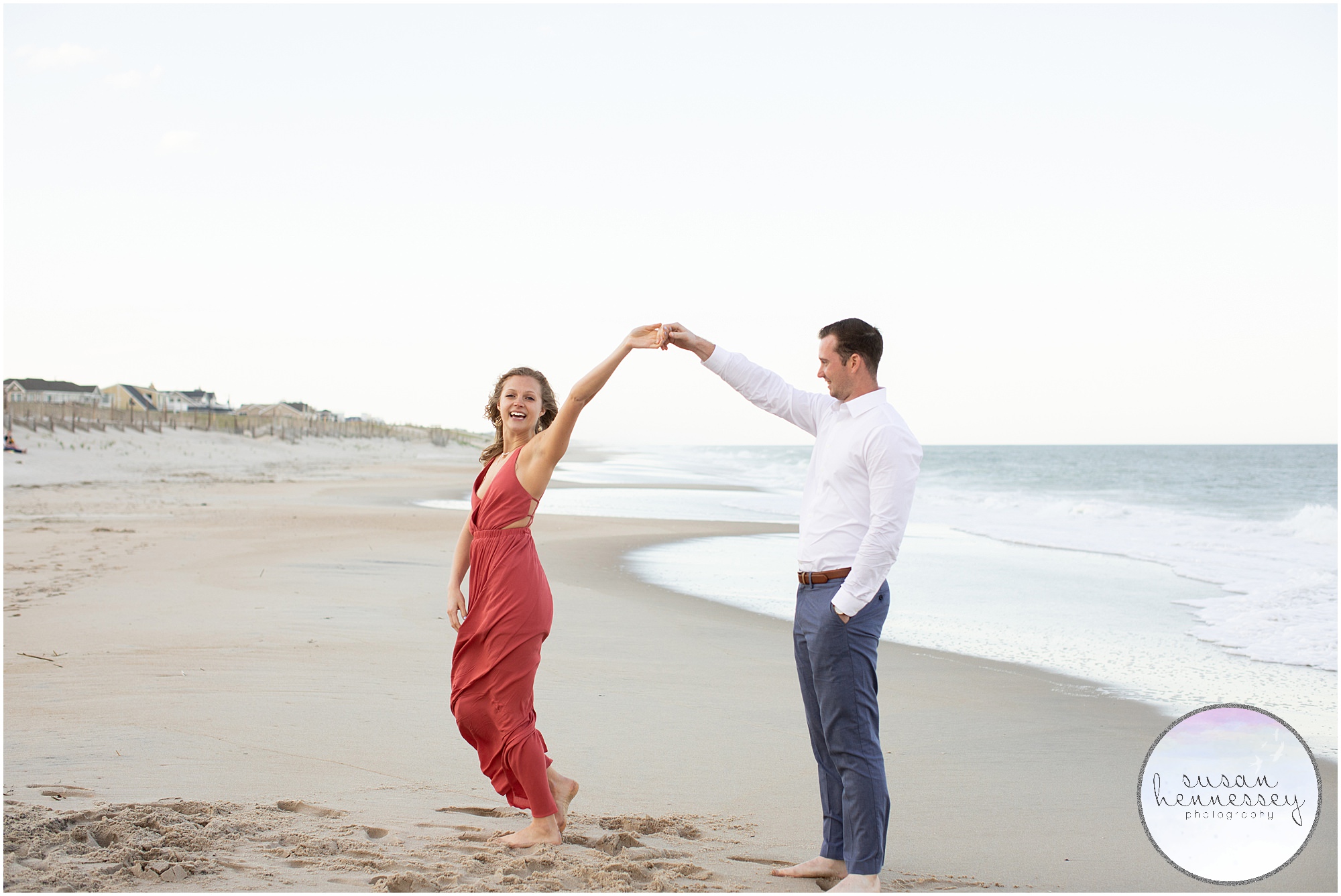 A groom twirls his future bride by the ocean.