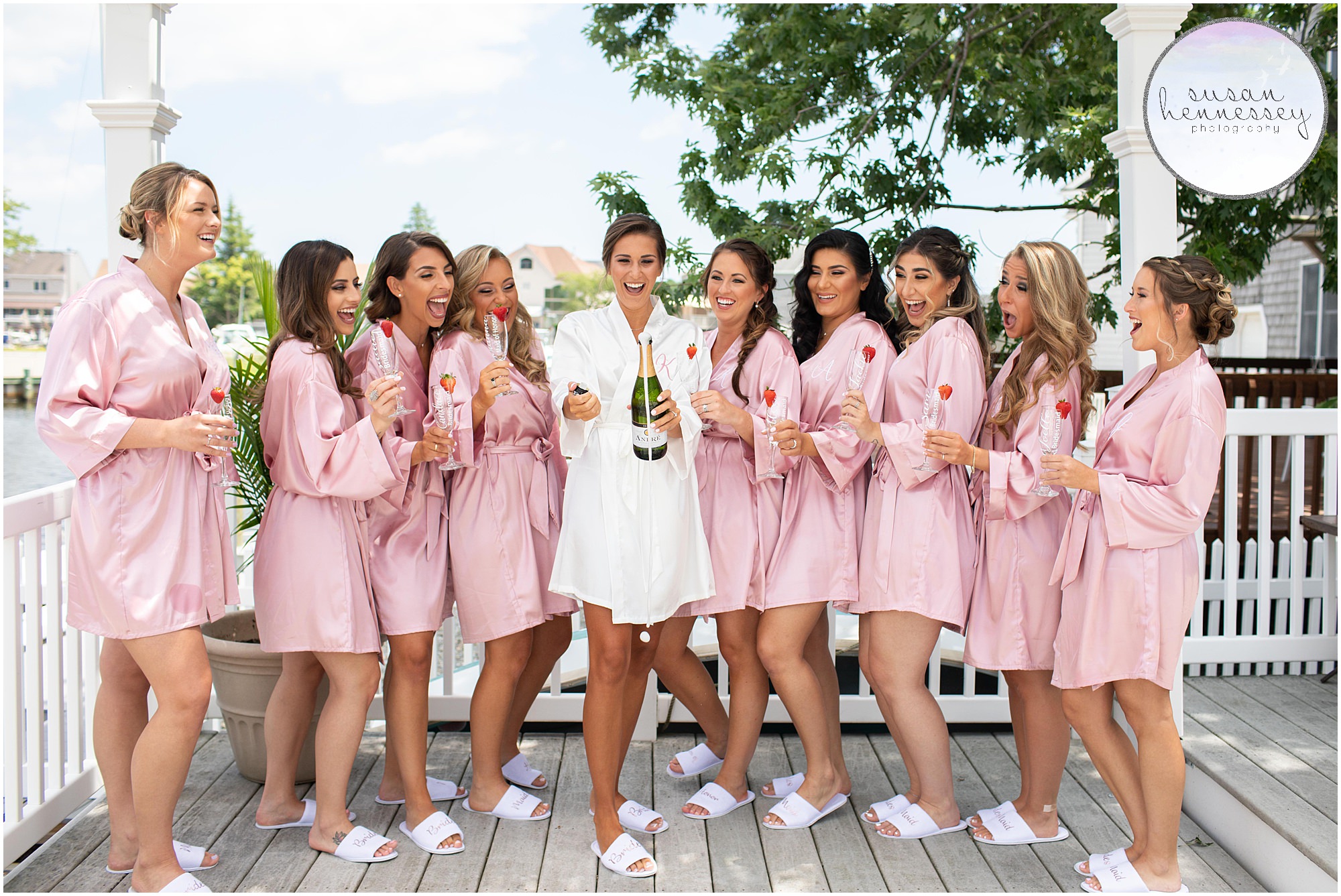 A bride and bridesmaids pop champagne in matching robes