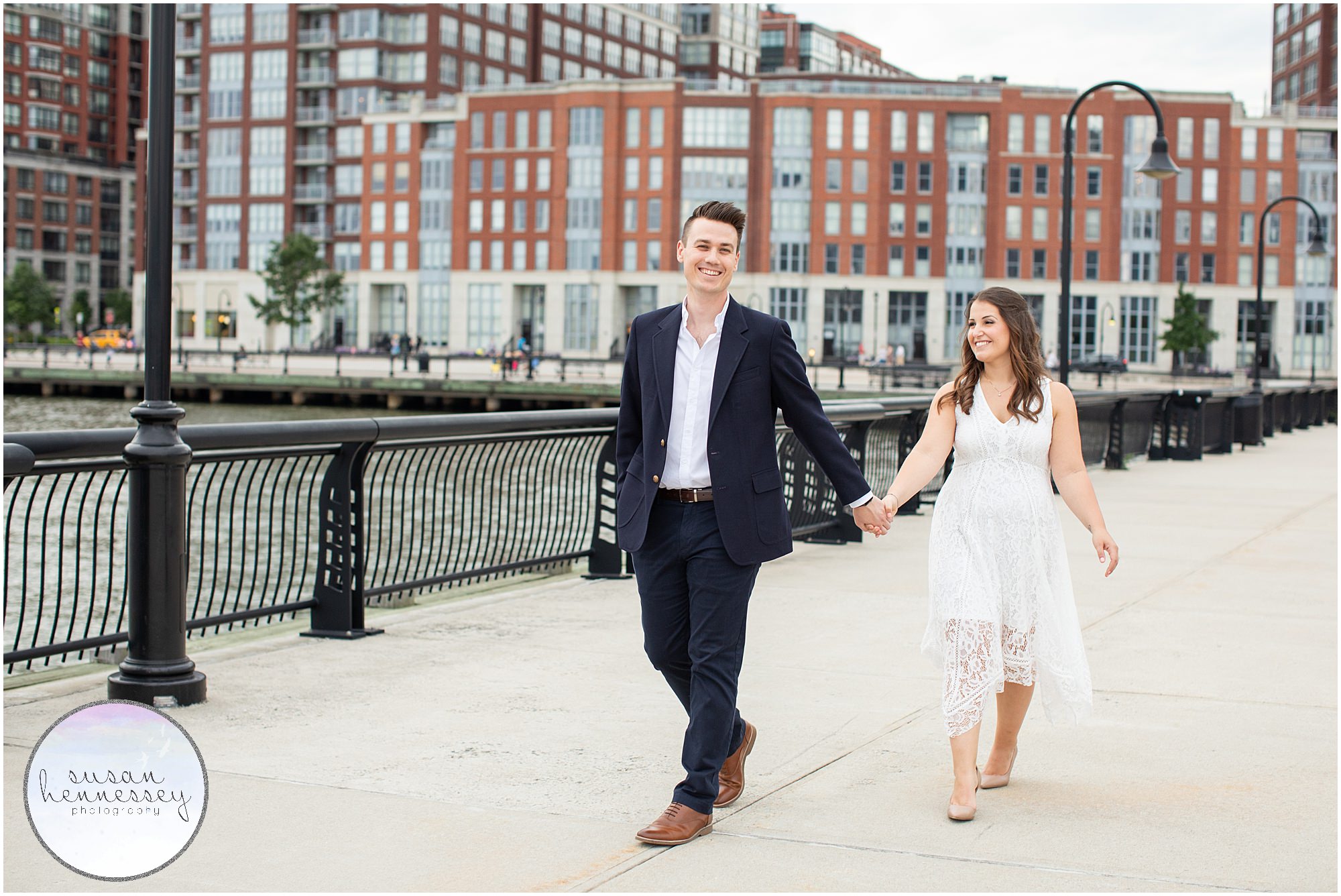 An engaged couple walks along the Hoboken waterfront. 