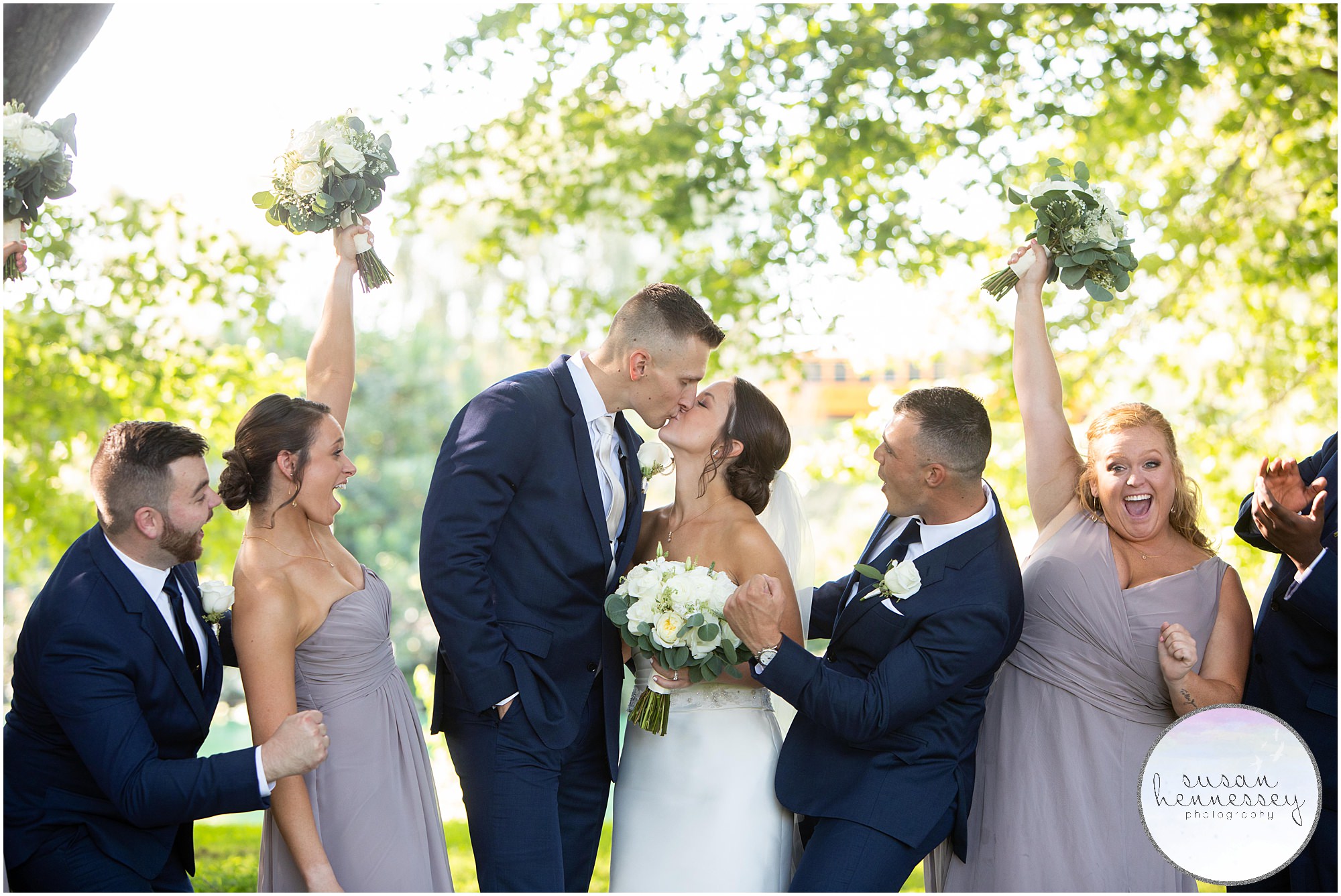 Bride and groom kiss with bridal party cheering them on!