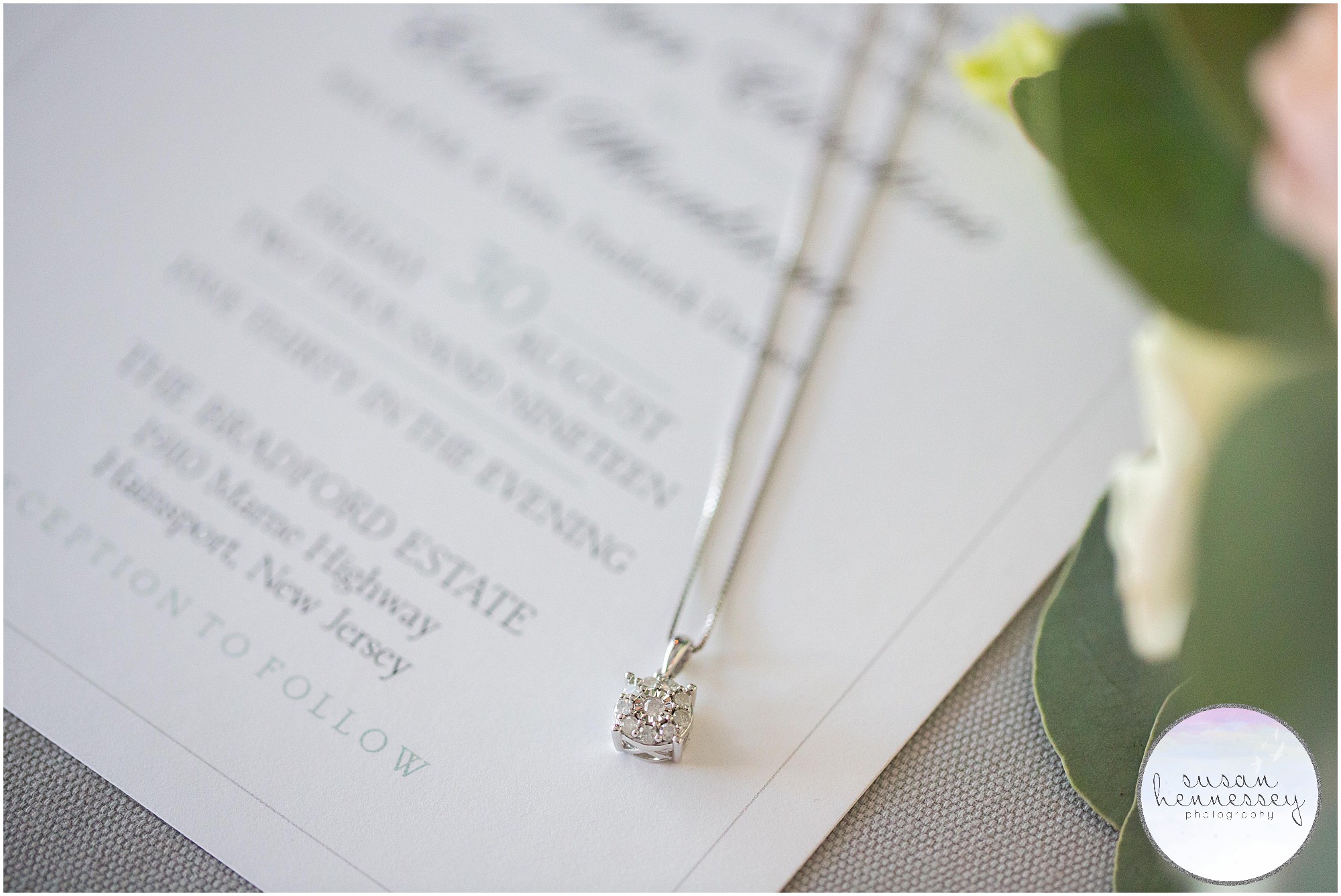 Bride's diamond necklace laying on invitation