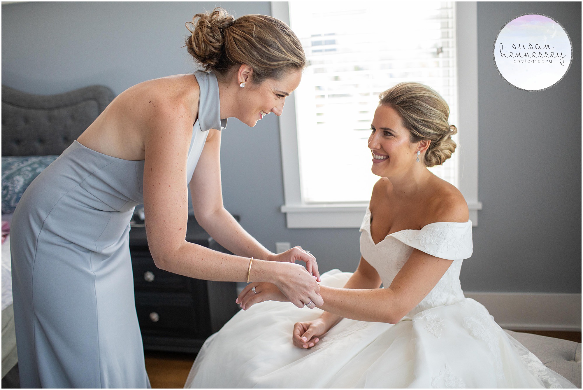 Maid of honor helps bride with her bracelet.