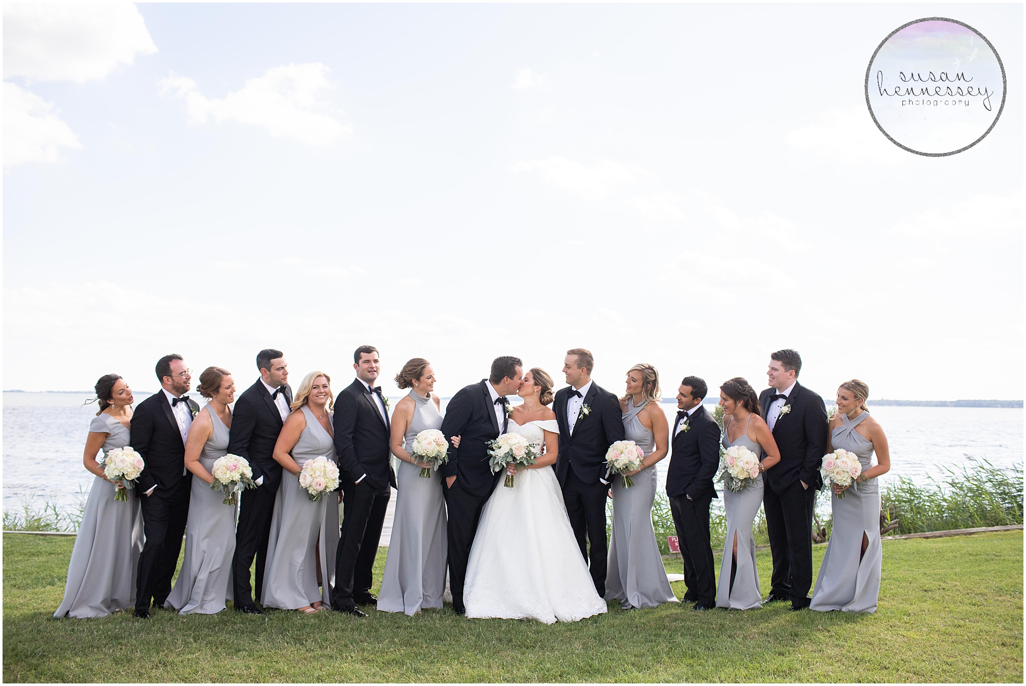 Bride and groom kiss with their bridal party looking on