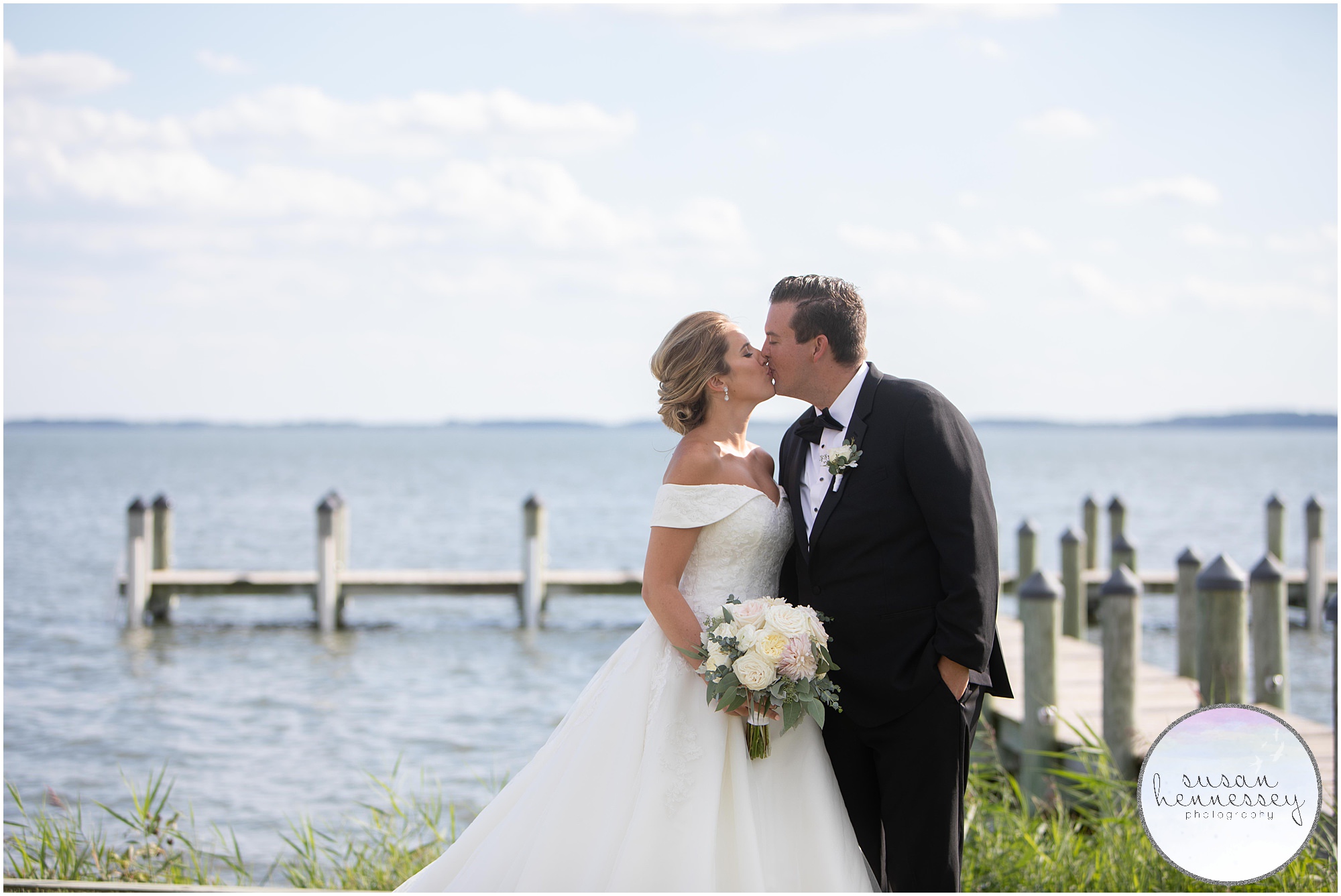 A bride and groom kiss in front of the pier at Rehoboth Beach Country Club