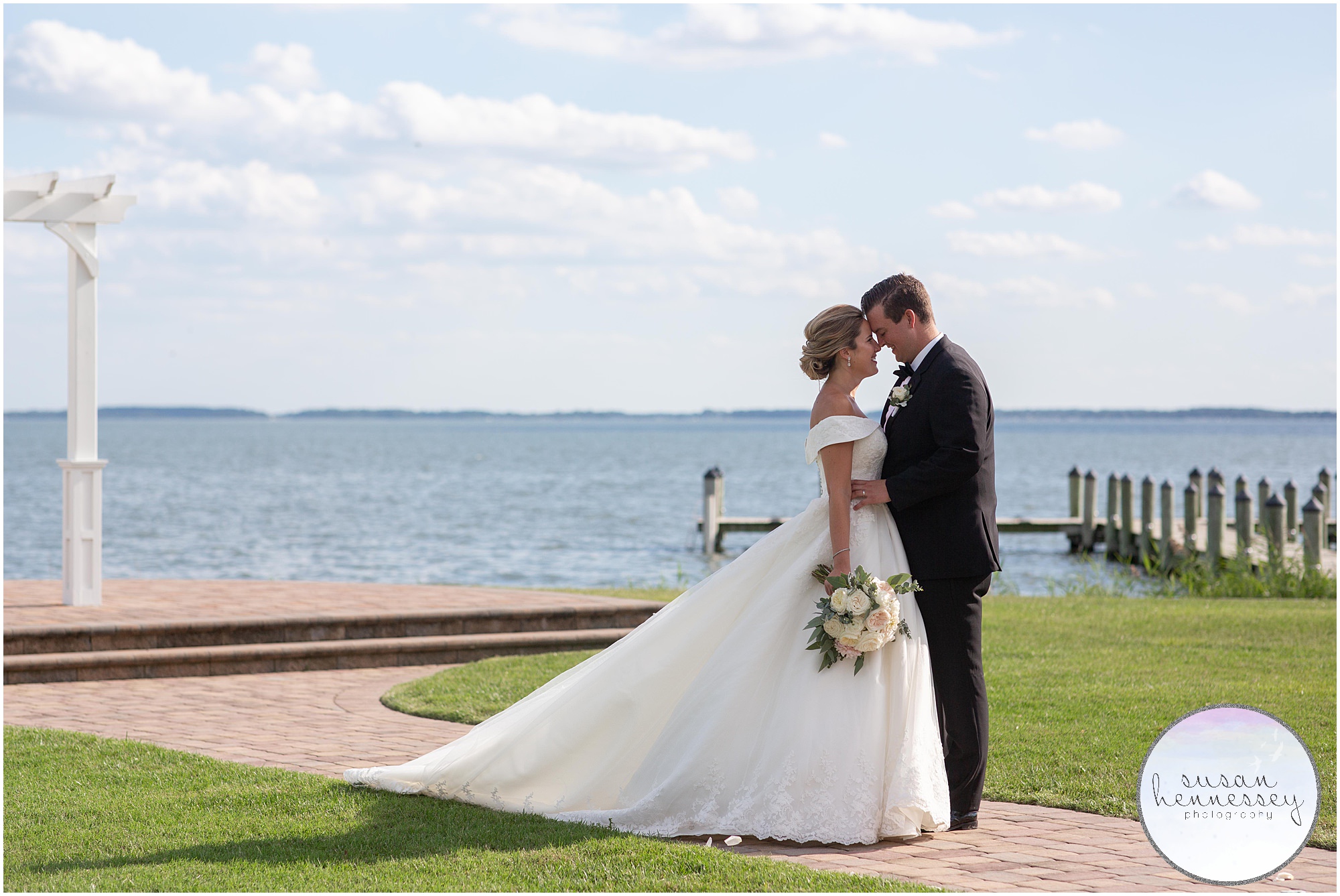 Couple pose in front of waterfront on their wedding day