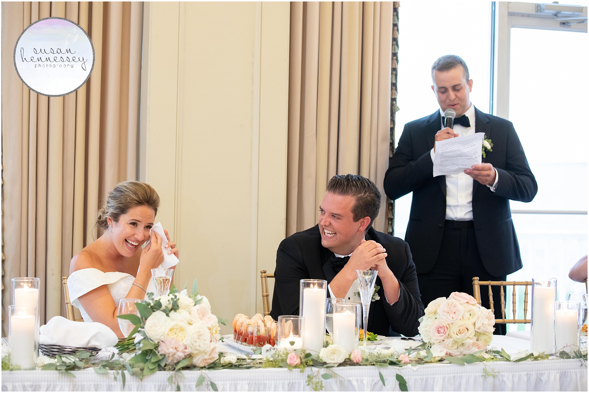 A bride and groom laugh during the best man's speech