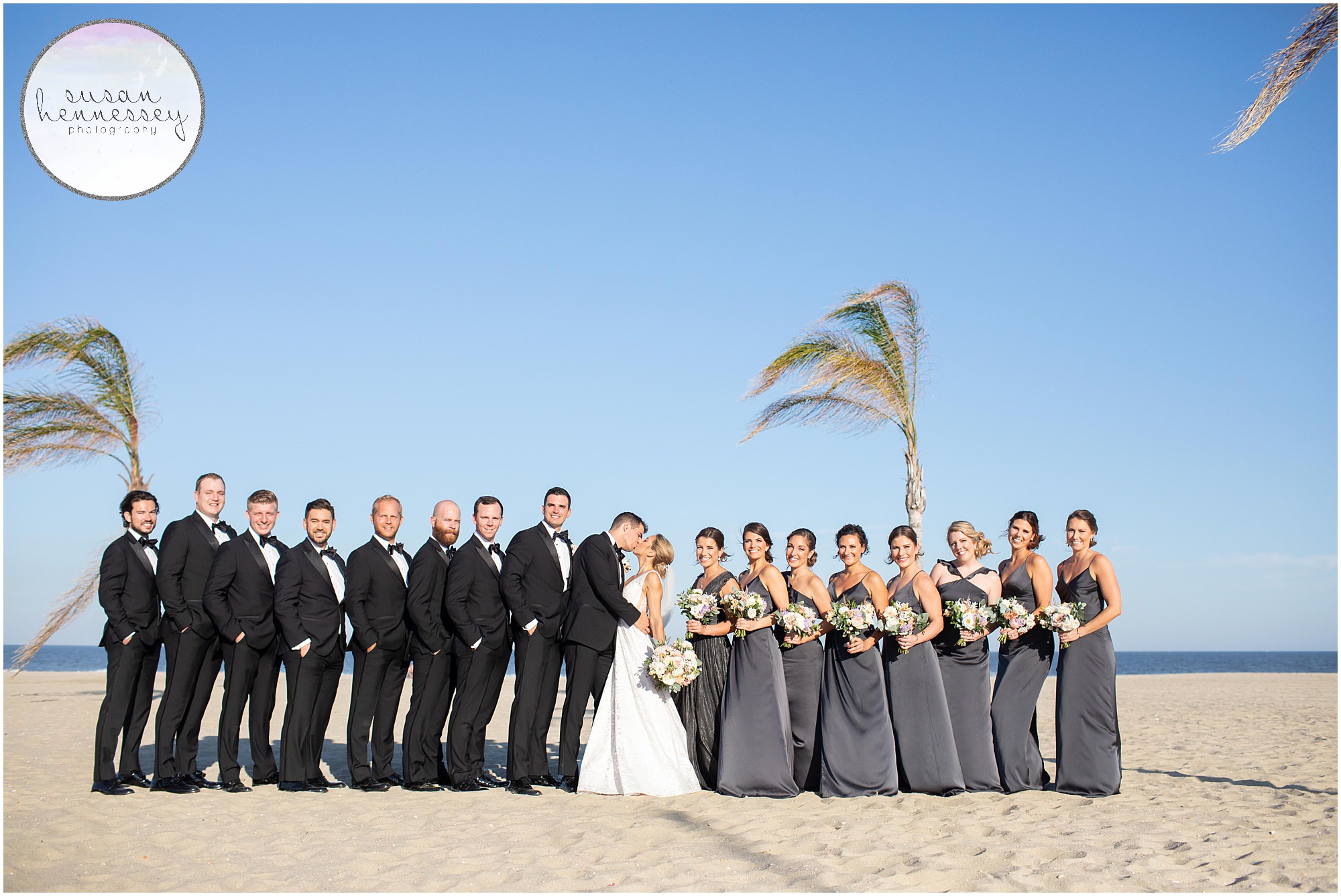 Bridal party on beach in front of ocean. 