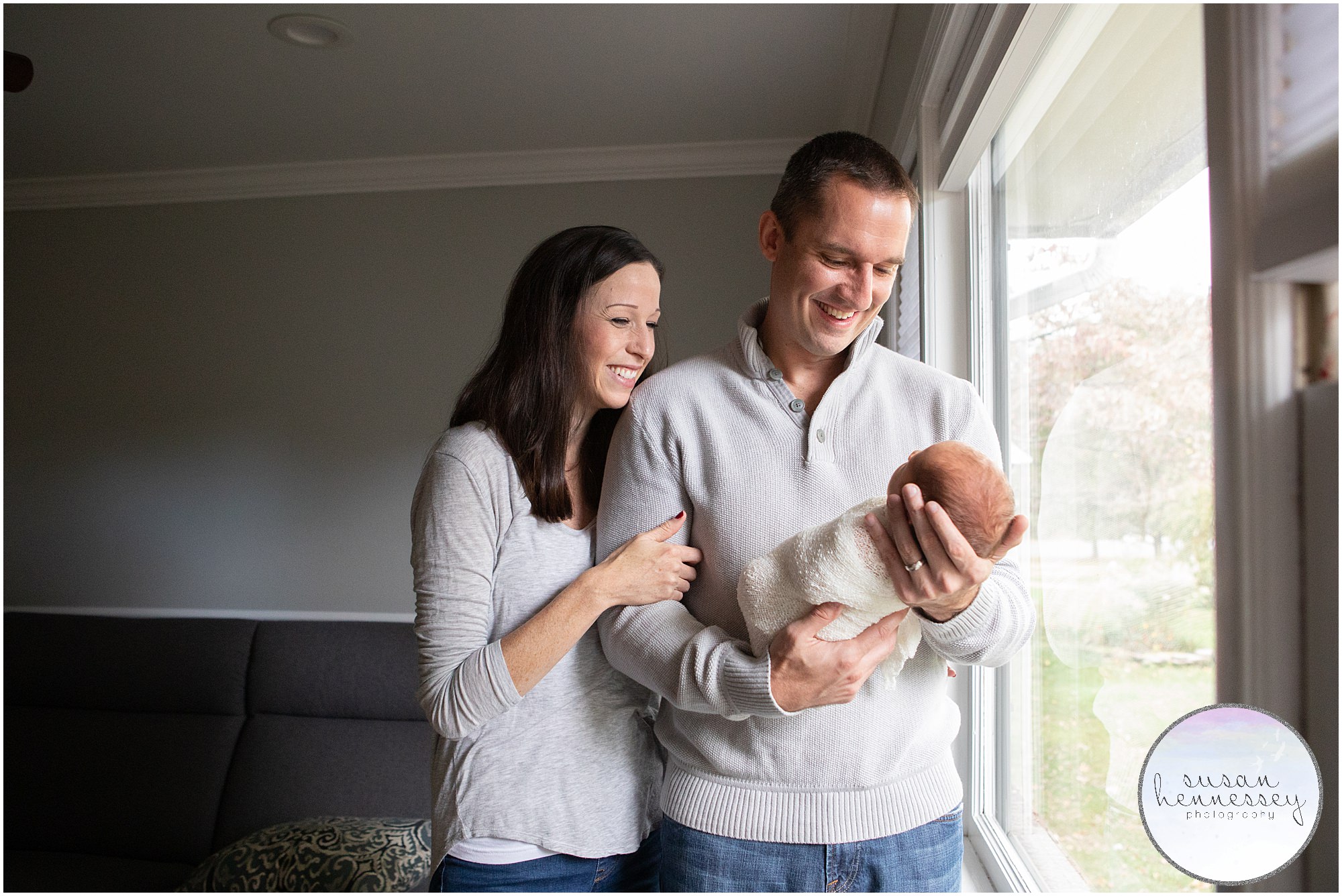 A happy couple pose with their newborn boy at their In home newborn session