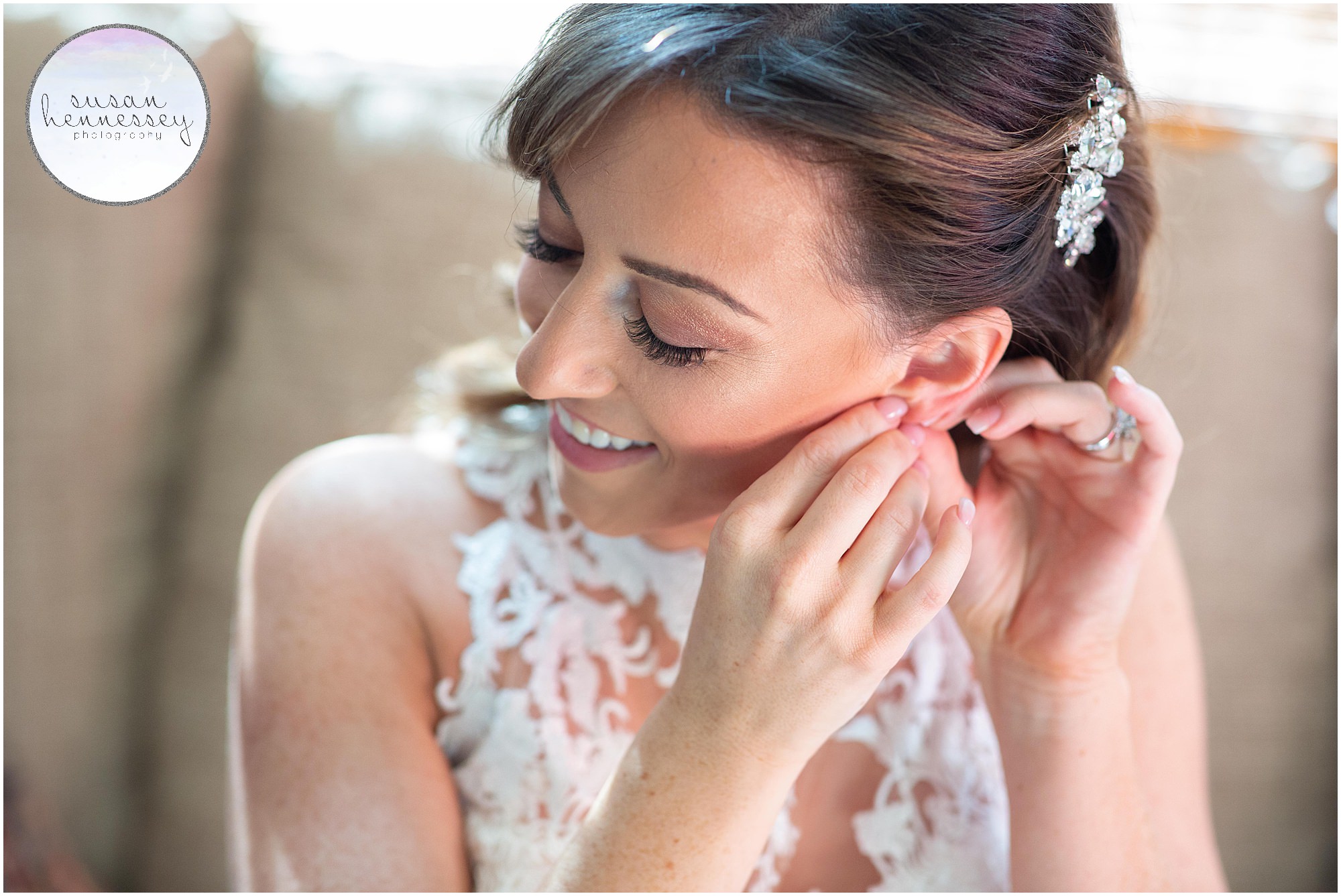 a beautiful and glowing bride puts on her wedding day earrings