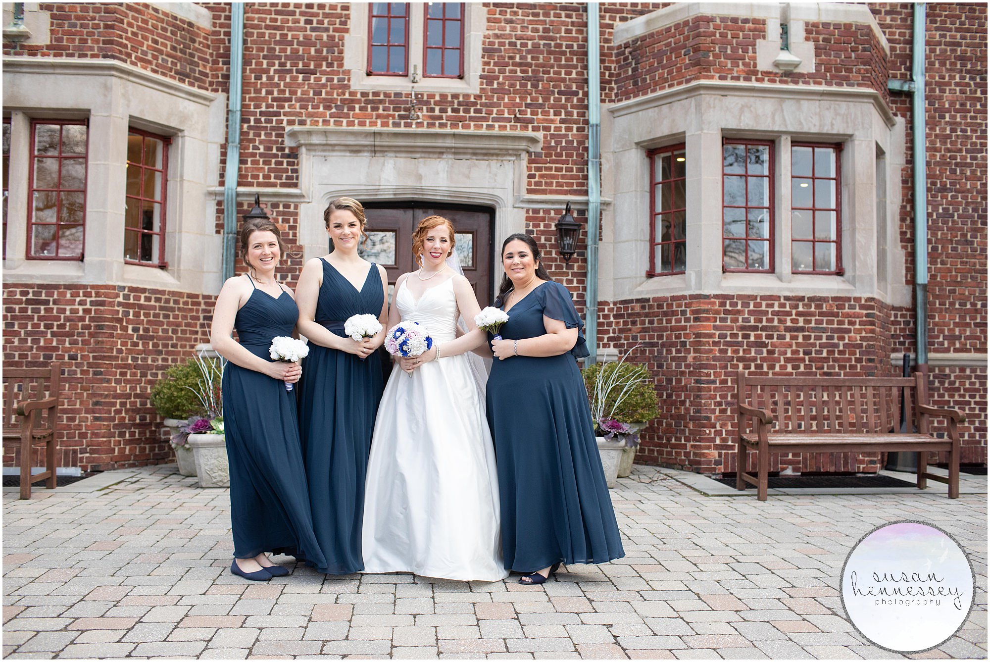 Bride and bridesmaids pose in front of Moorestown Community House at winter wedding