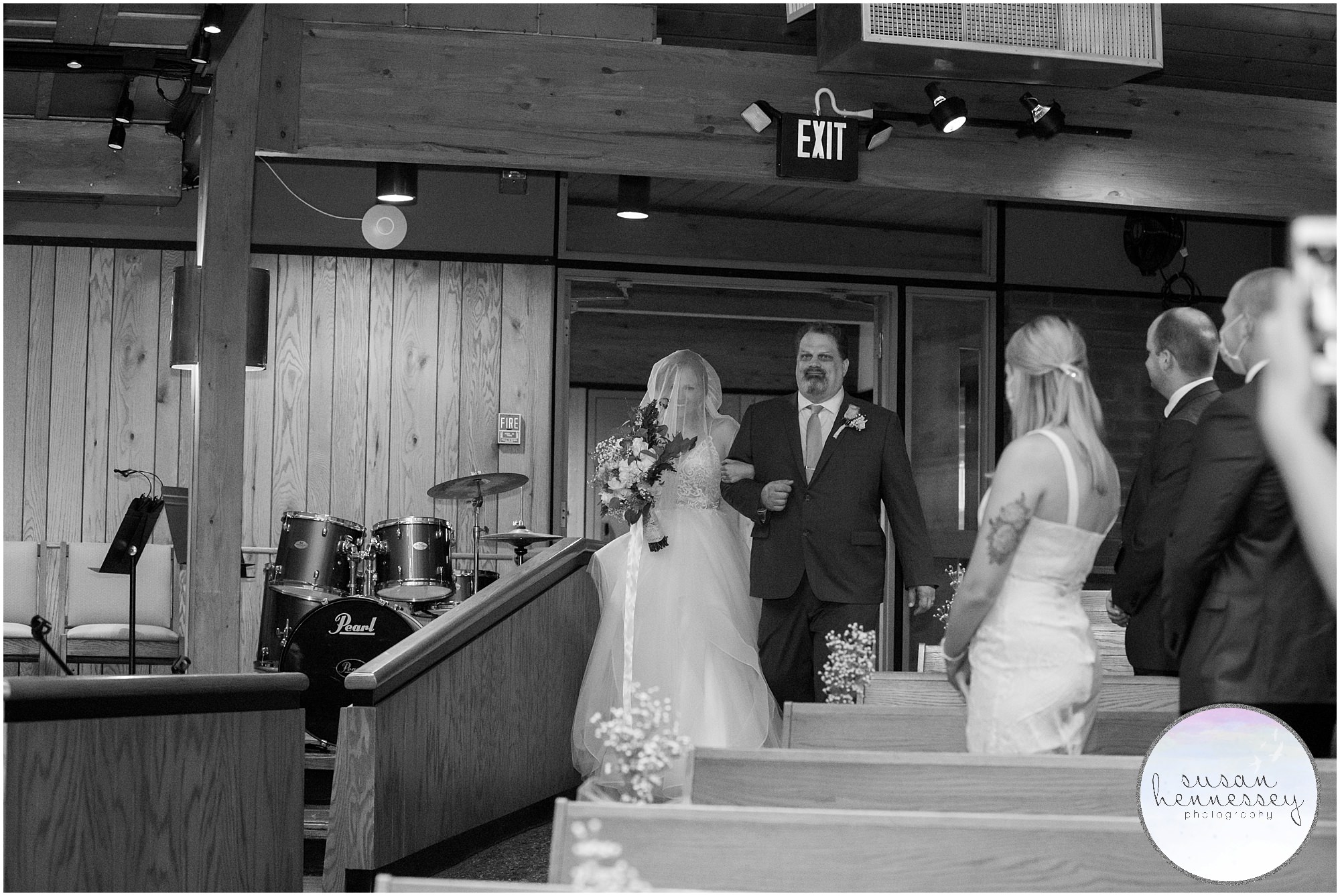 Black and white image of father walking bride down the aisle