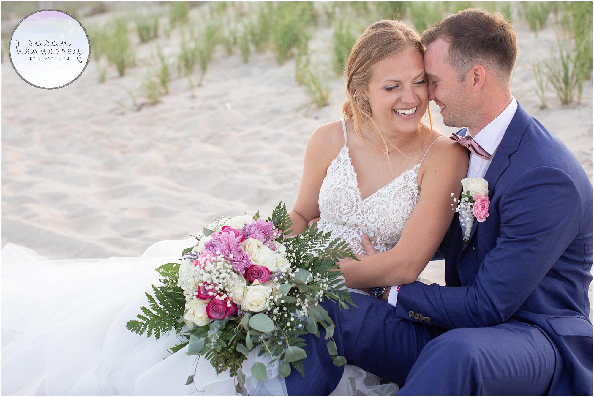 A couple laughs in the sand at Summer beach wedding
