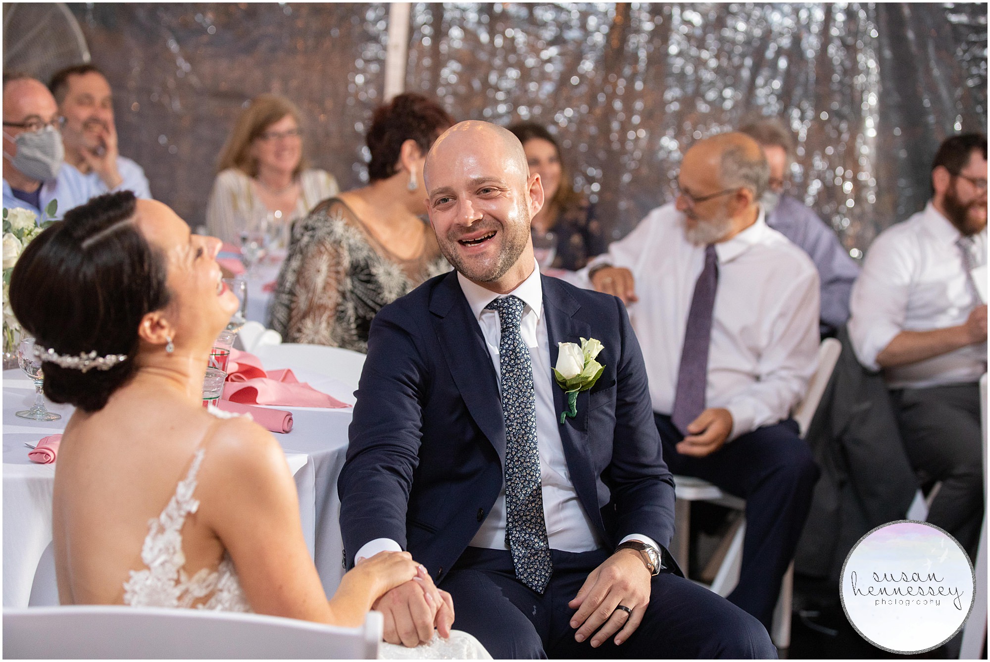 Bride and groom laugh at toasts at tented backyard wedding