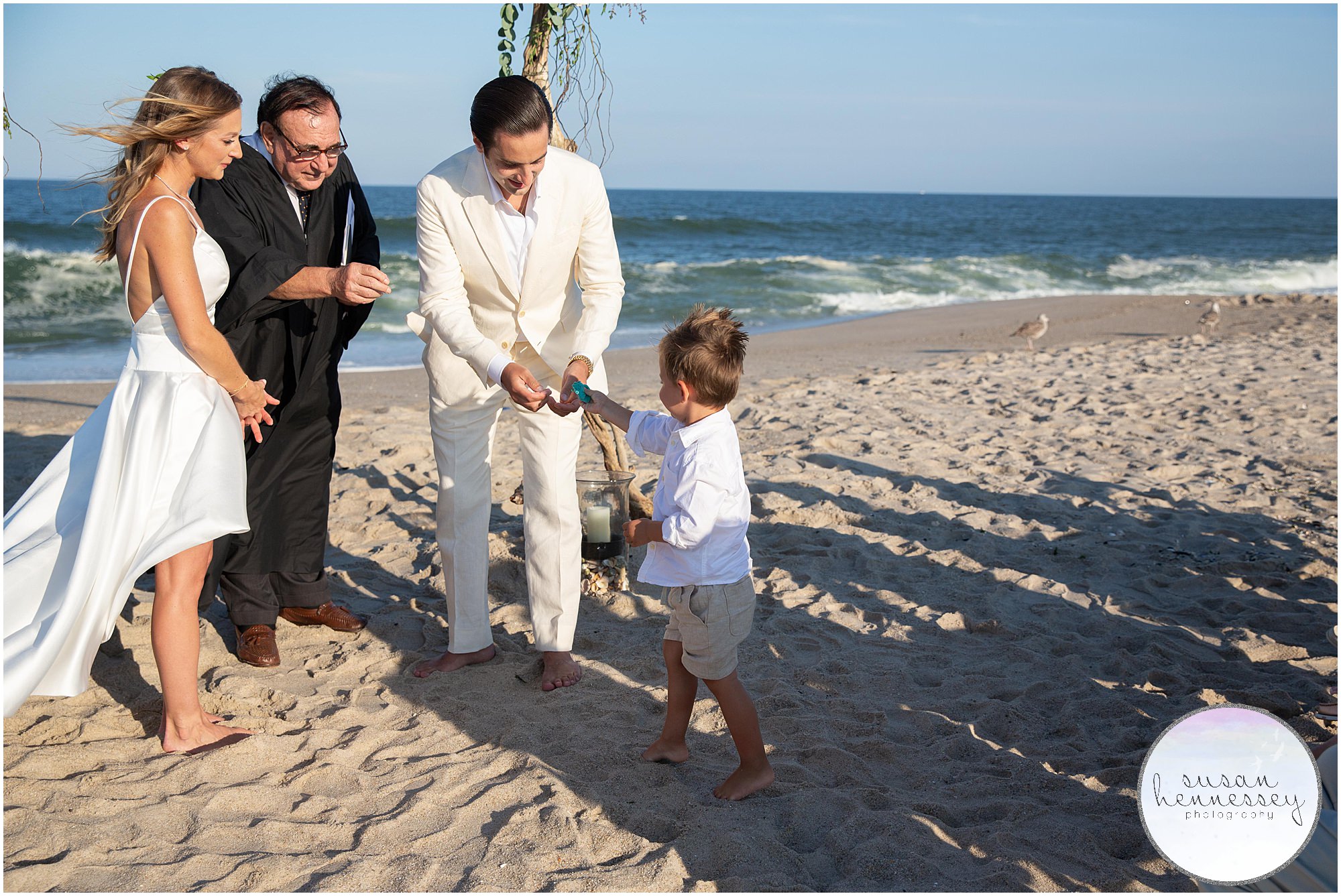 The ring bearer hands the groom the rings at beach wedding