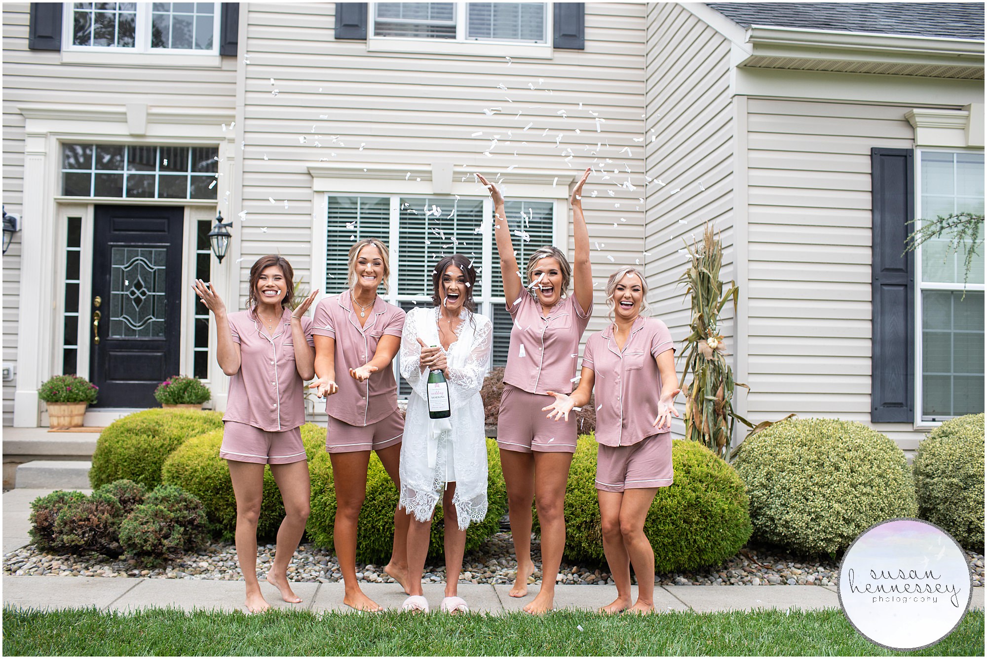 Bride and bridesmaids in matching pajamas pop champagne and throw confetti before Renault Winery wedding