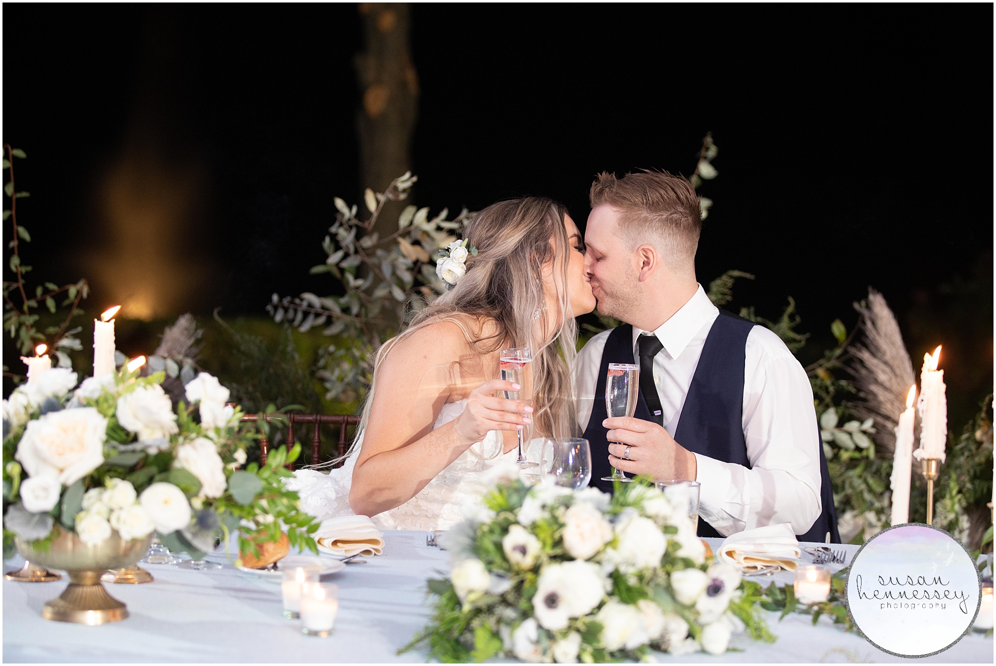 Bride and groom kiss at sweetheart table at Windows on the Water at Frogbridge Wedding