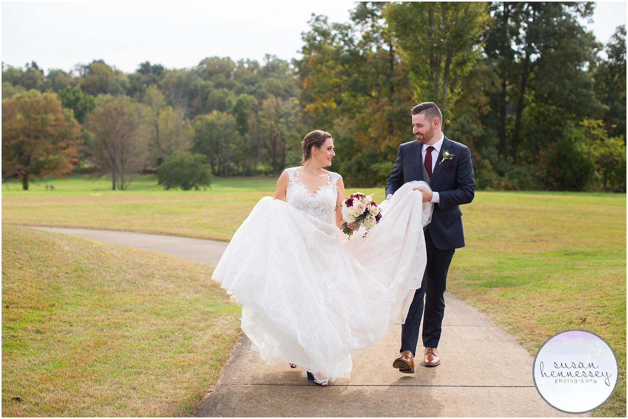 Groom helps bride carry her dress at Fall Wedding at Old York Country Club