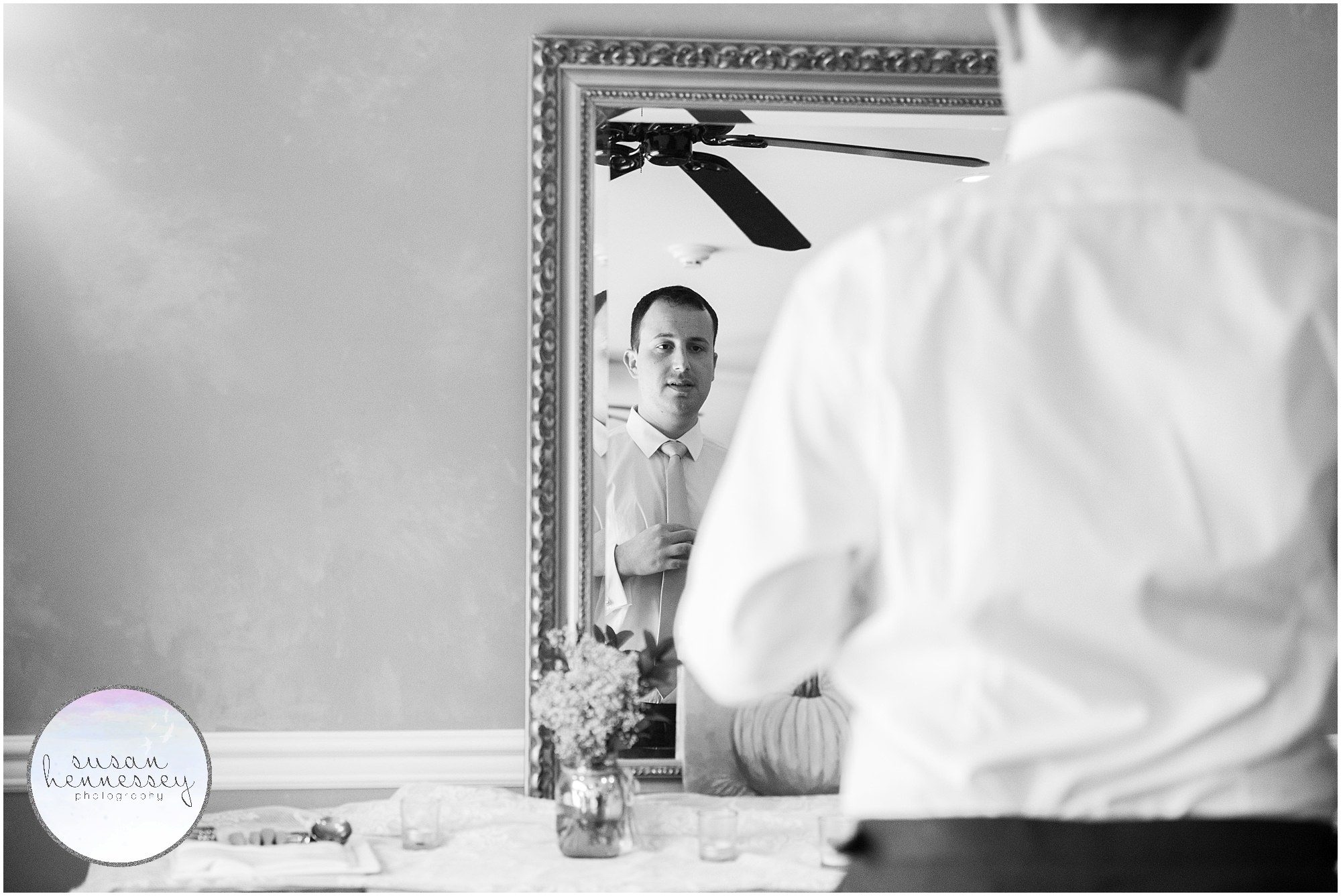 Black and white portrait of groom adjusting tie at Andre's Lakeside Dining Microwedding