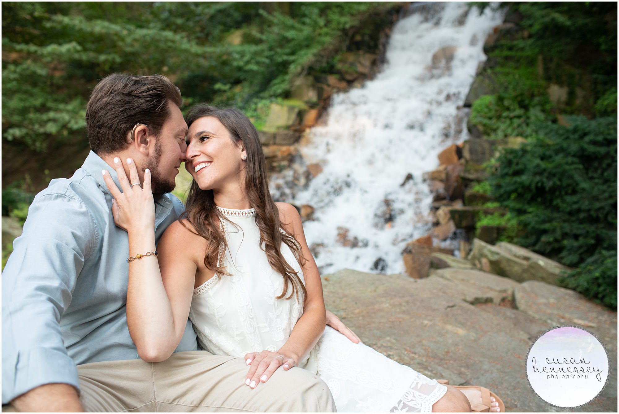 A couple by the waterfall at their engagement session at Longwood Gardens