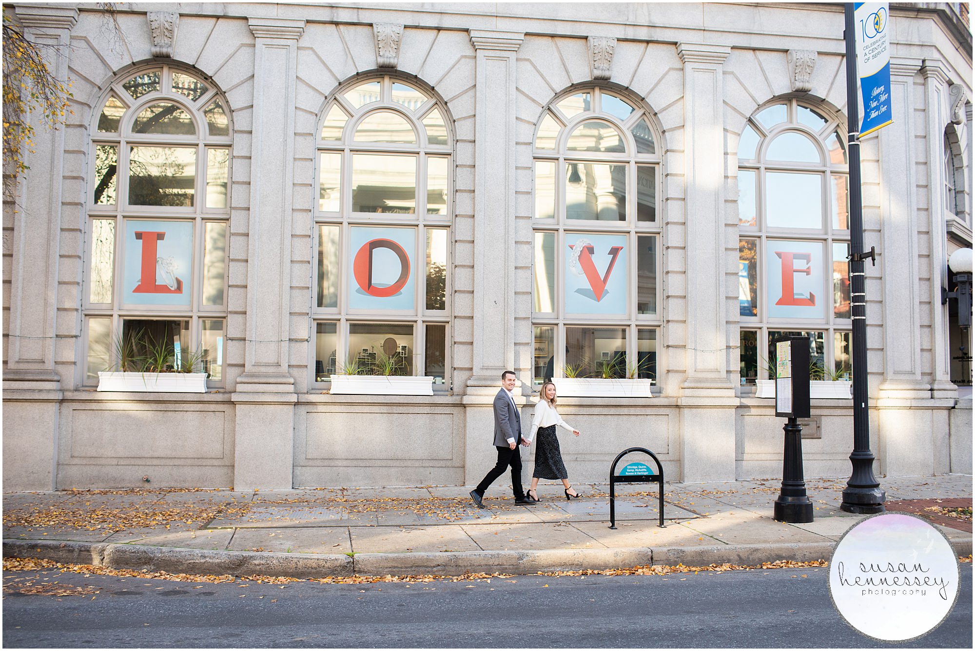 A couple hold hands while walking at their Downtown Frederick Engagement Session