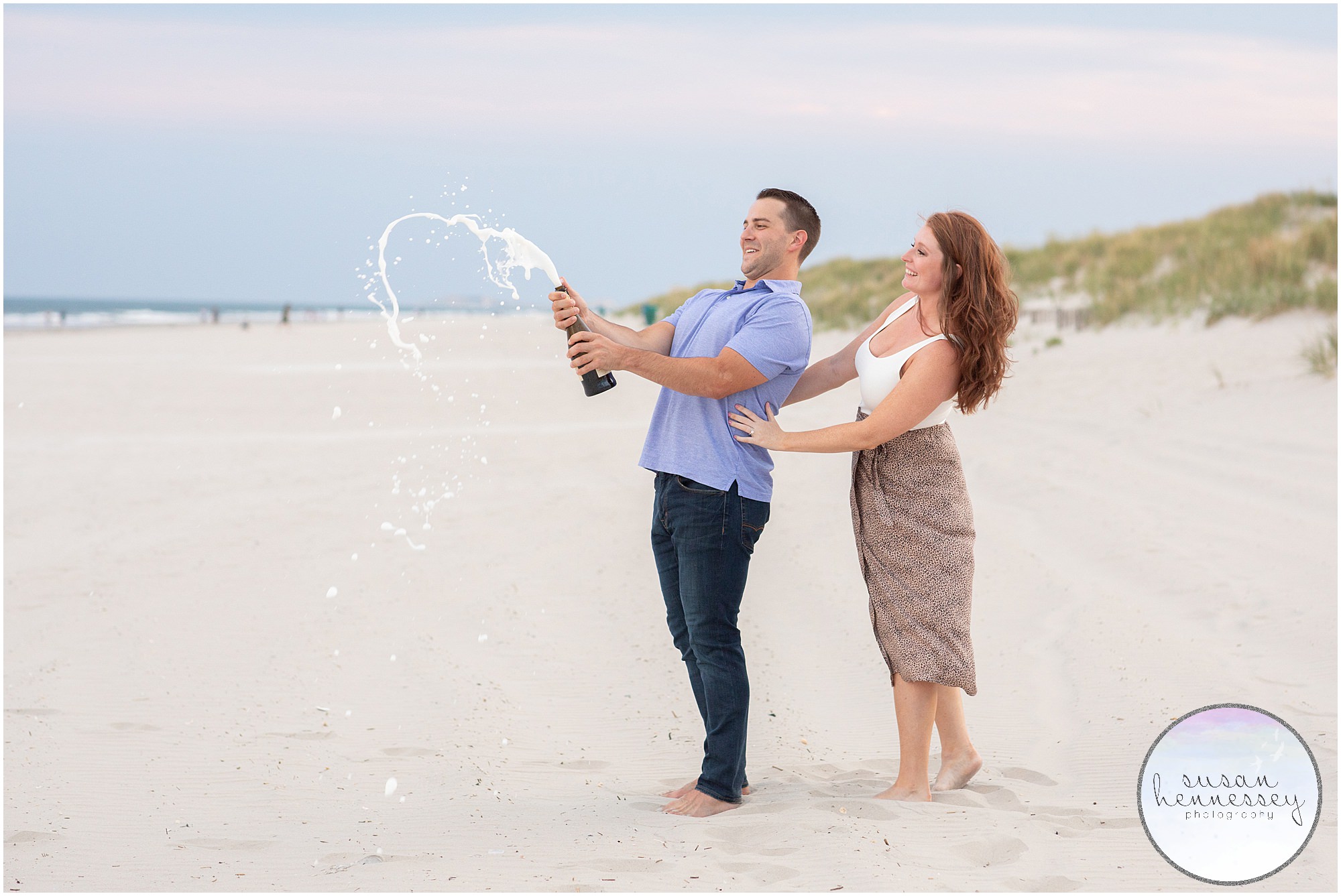 A couple pops champagne on the breach after their surprise proposal in Stone Harbor
