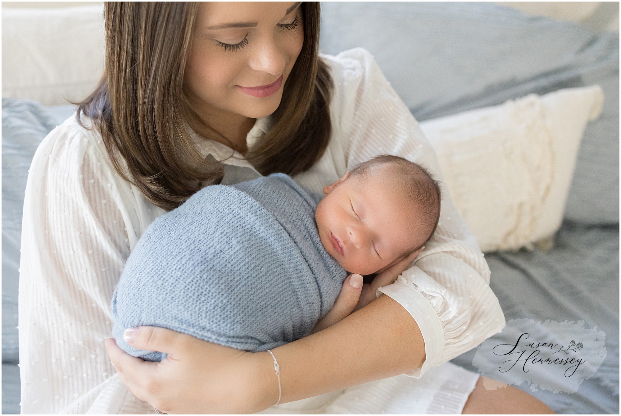 Mother holds wrapped newborn during in home newborn session