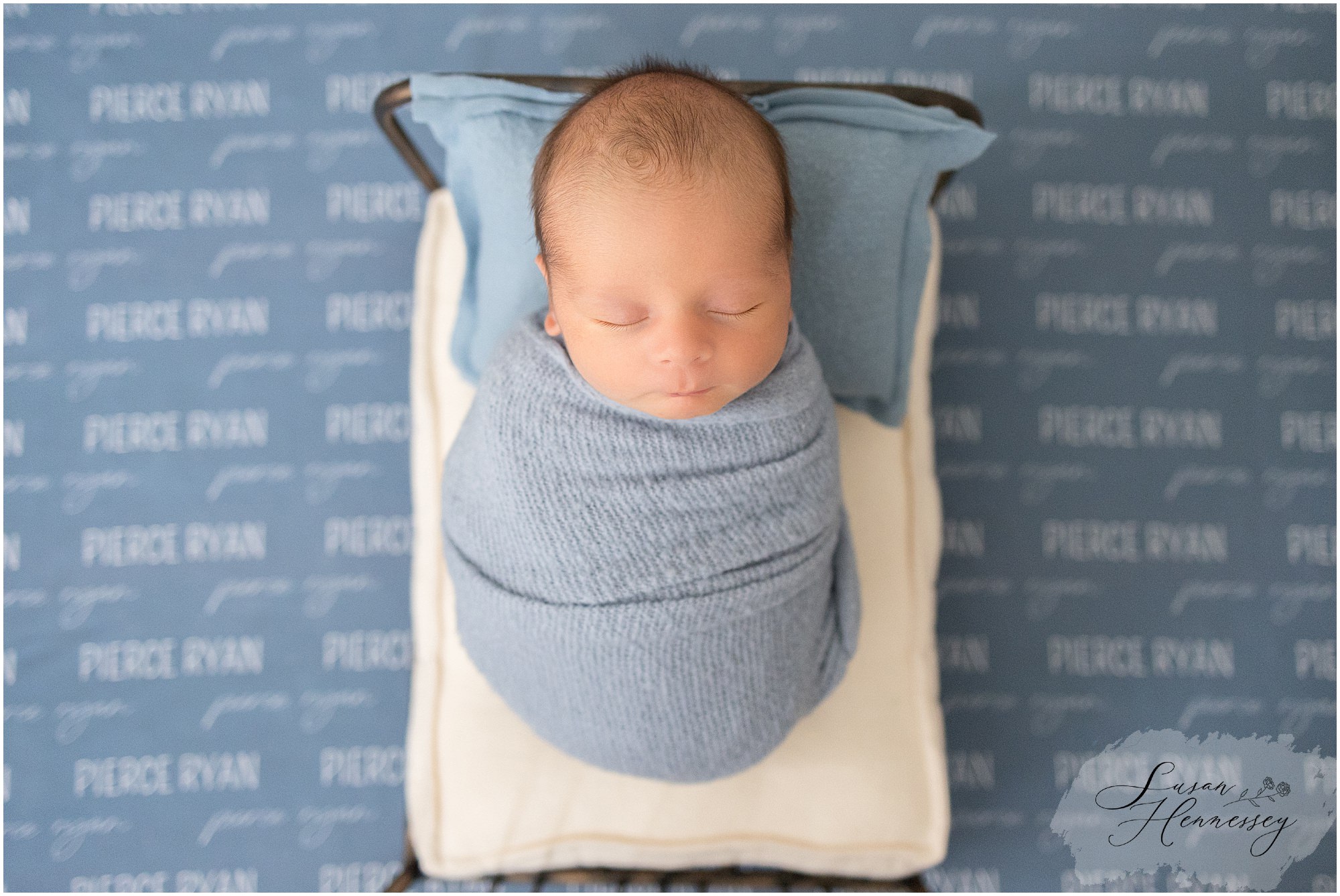 Newborn baby laying in bed for newborn session on caden lane blanket with his name on it. 