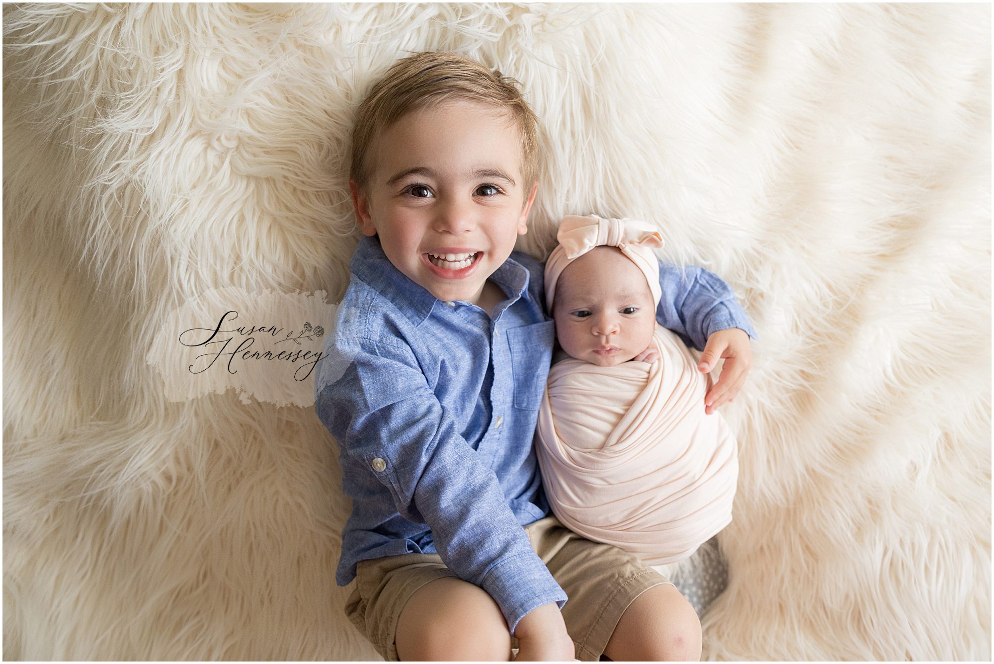 Proud big brother holding newborn baby sister during studio newborn session