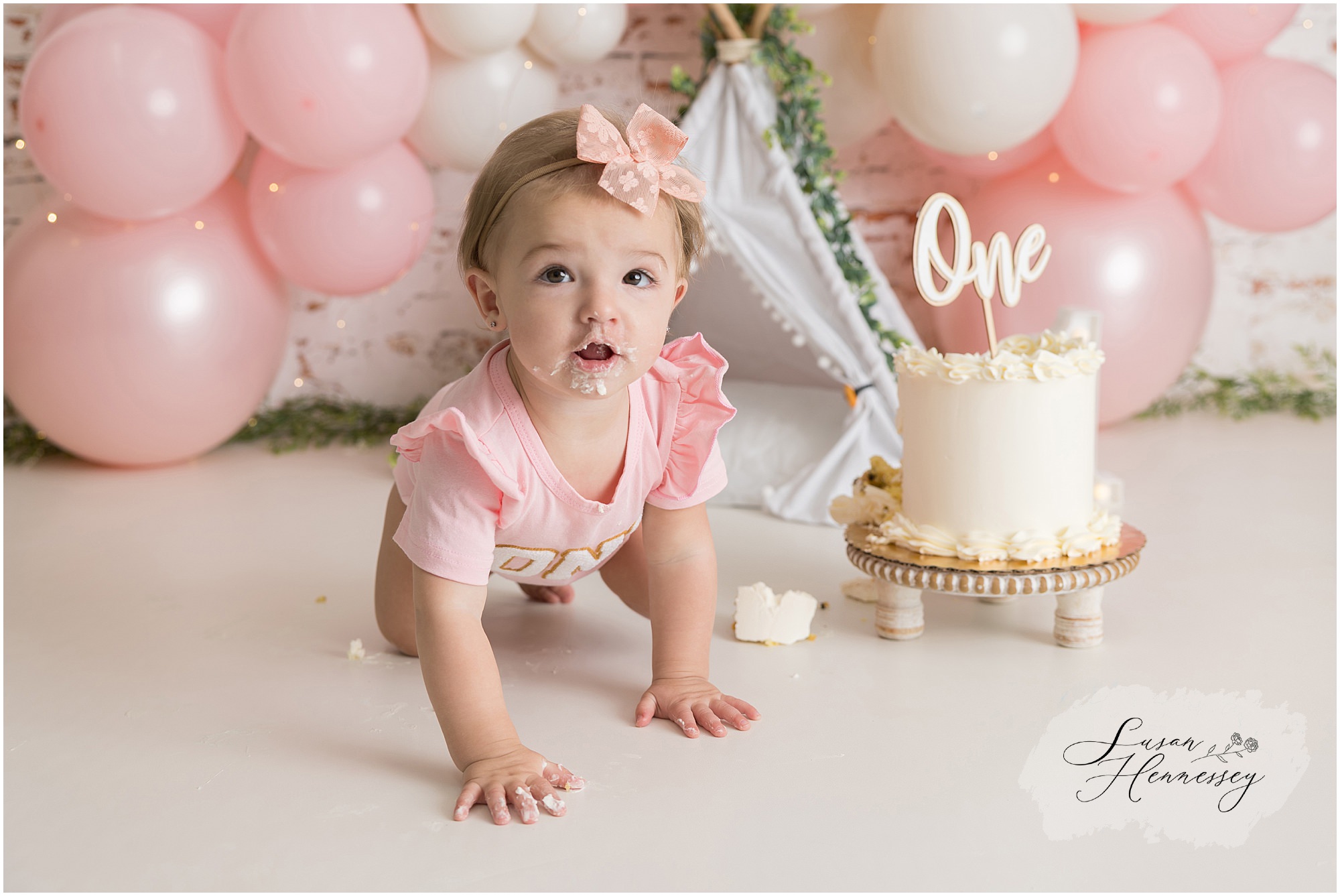 Baby girl covered in frosting during a fun first birthday cake smash photography session