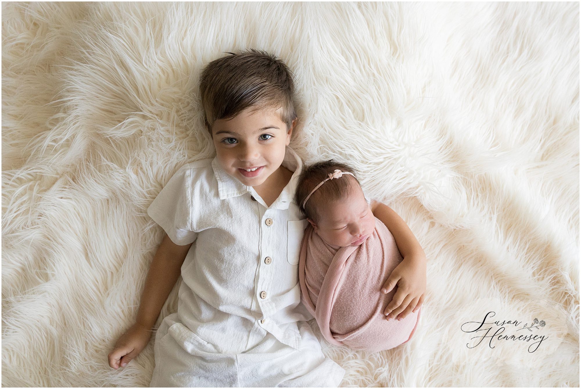 Sibling photo with proud big brother holding newborn baby sister