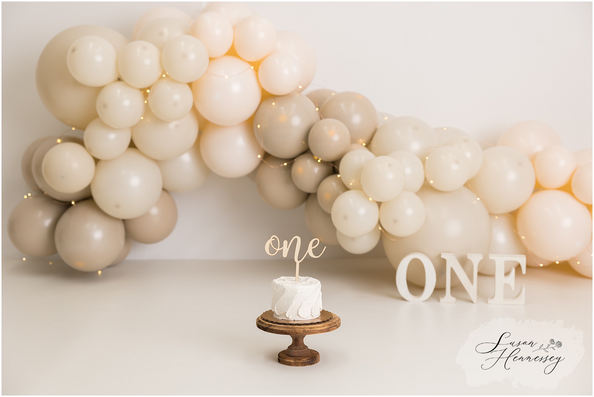 Neutral cake smash session setup with custom brown and tan balloon arch